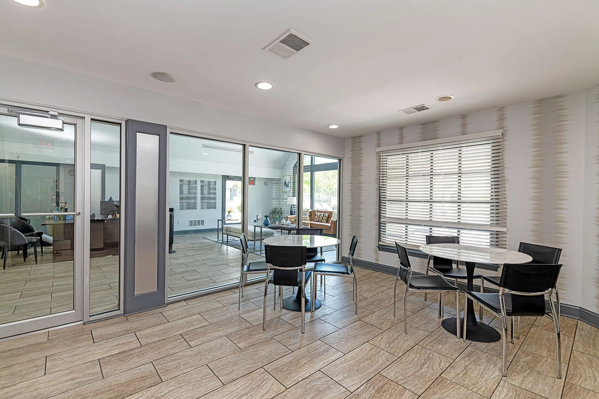 Contemporary communal area with sleek tiled flooring, modern glass walls, and stylish seating.