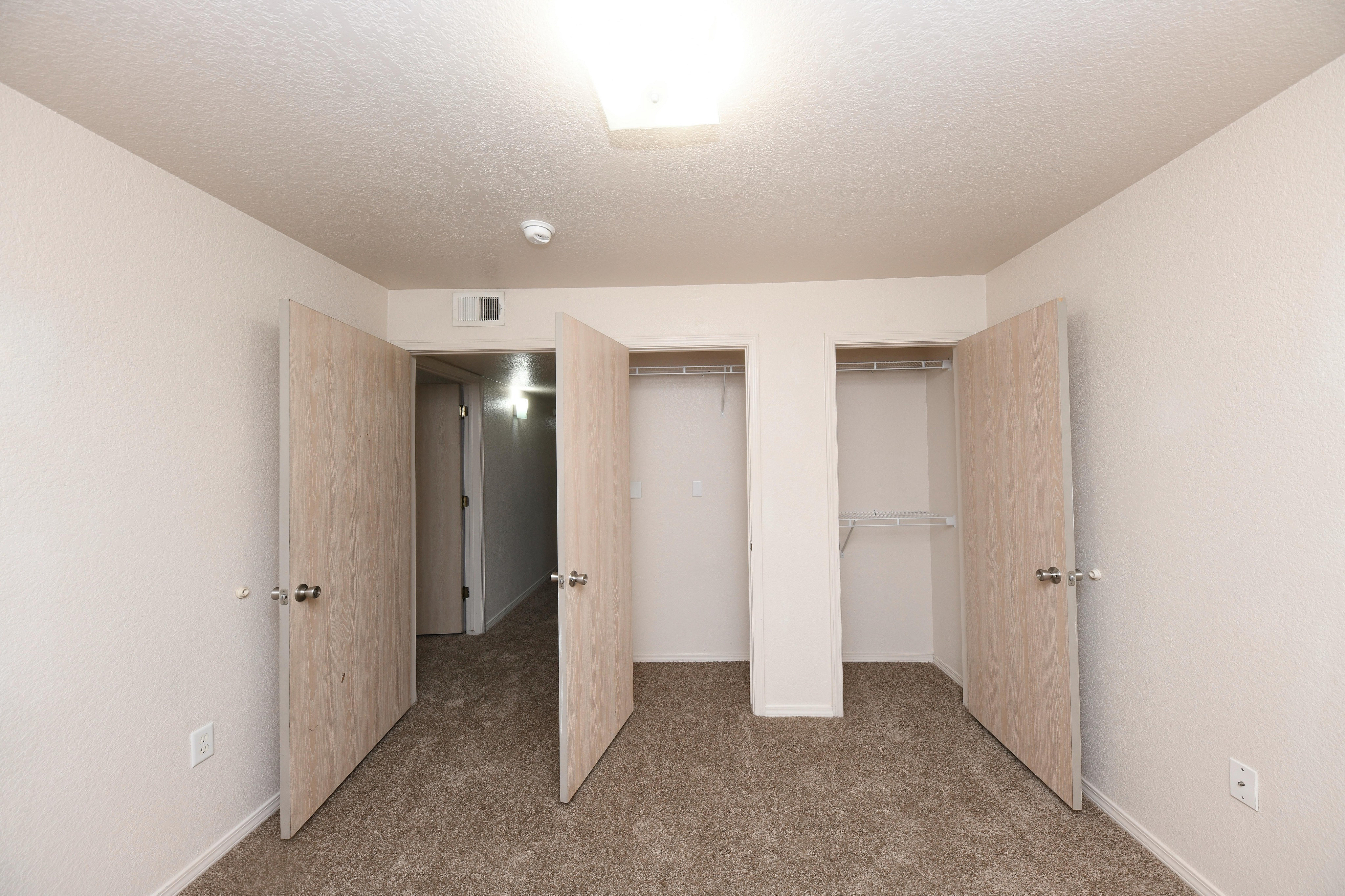 Bright and spacious apartment bedroom with plush carpet, ample closet space, and modern white walls for a fresh look.