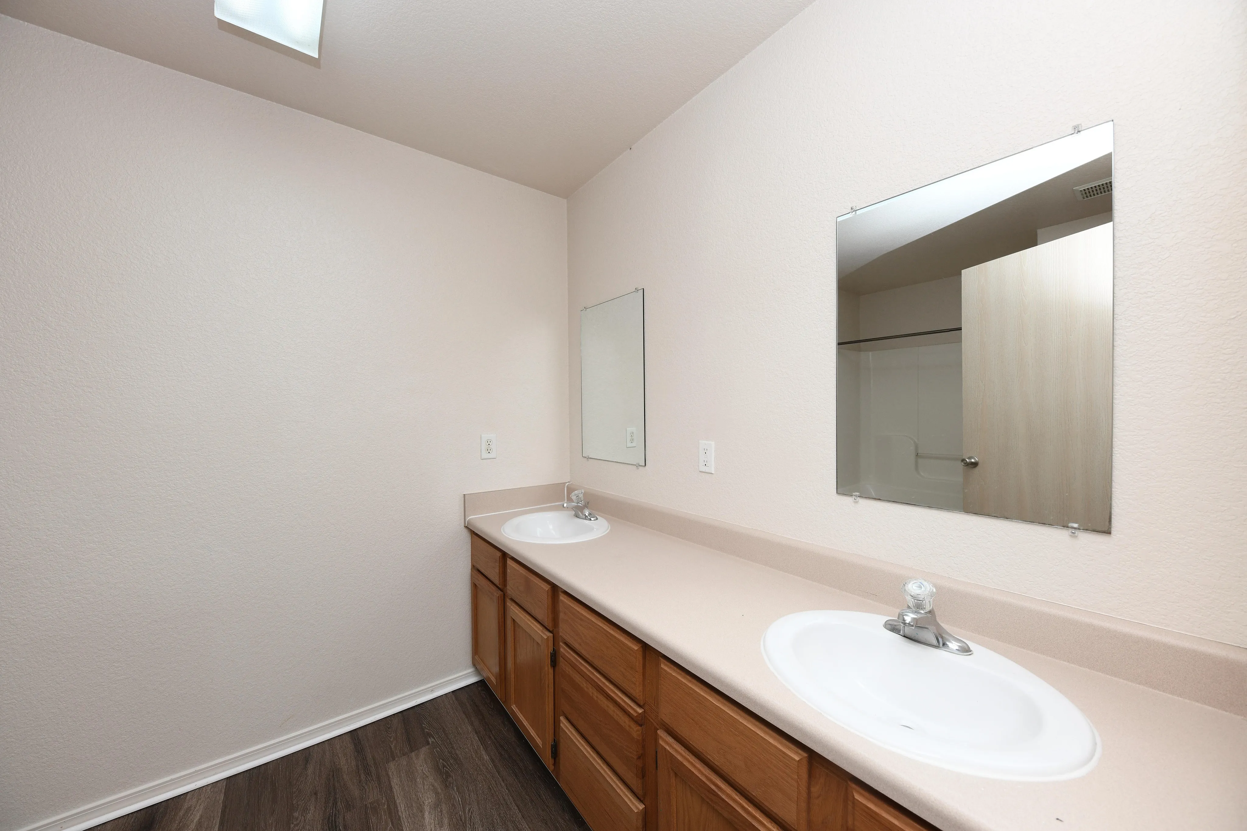 Modern bathroom with elegant dual sinks, spacious vanity, and warm wood cabinetry, perfect for shared comfort and style.