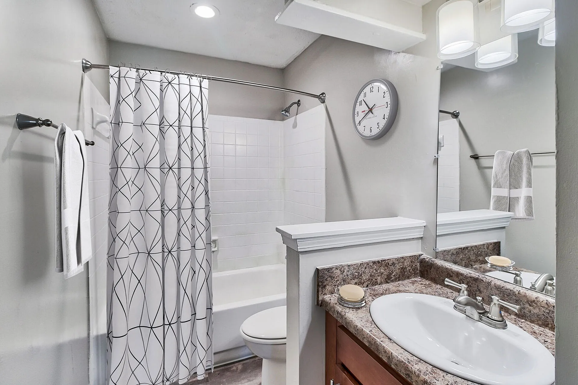 Bright, modern bathroom featuring elegant granite countertop, stylish vanity, and chic shower curtain with abstract design.