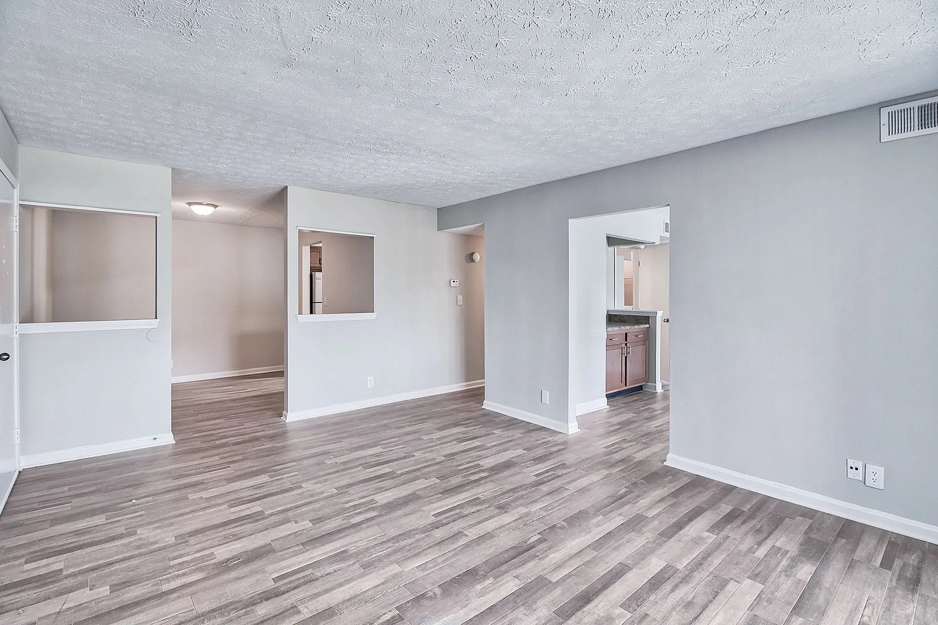 Bright and spacious living area with modern wood flooring and open kitchen view.