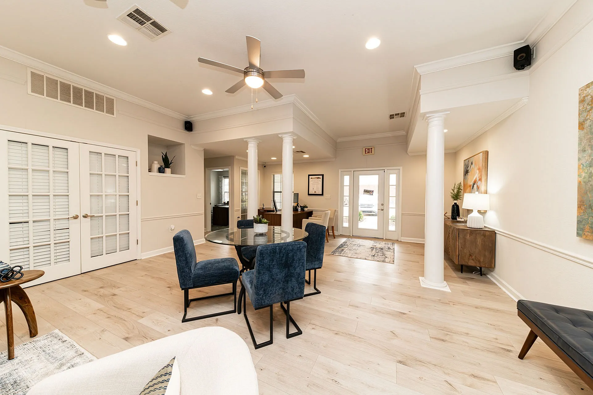 Elegant open-space interior featuring a modern dining area with plush blue chairs, chic lighting, and stylish decor.