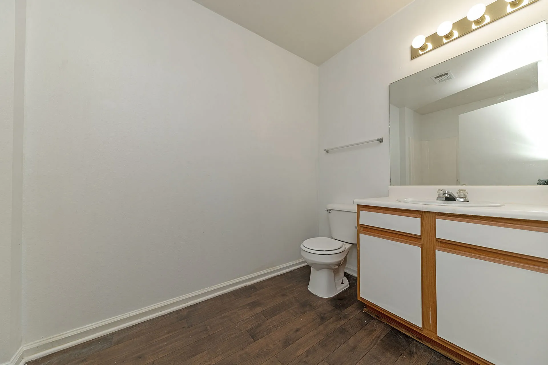 Bright and modern bathroom with sleek wooden flooring, contemporary vanity, and stylish overhead lighting.
