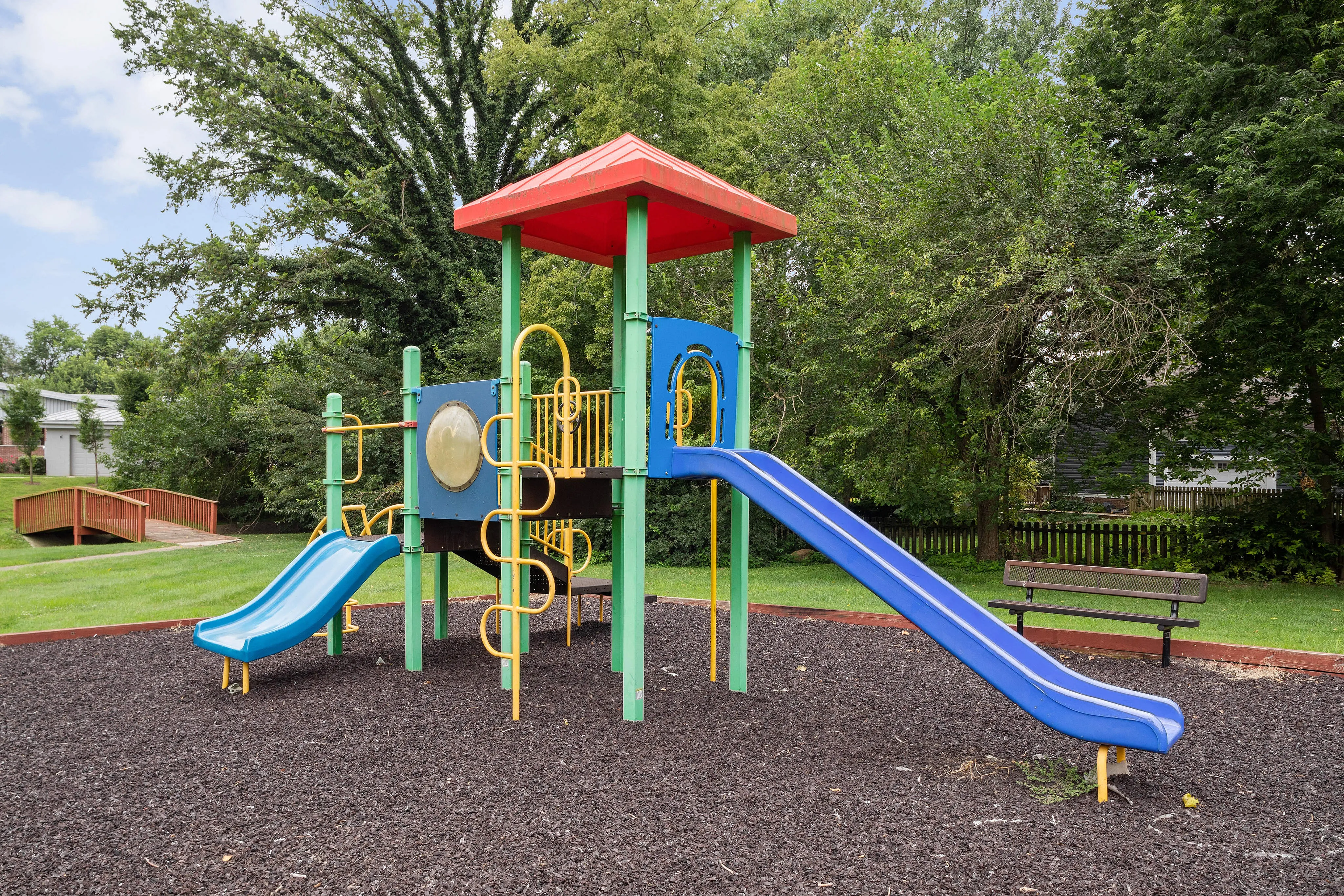 Charming and vibrant playground with colorful slides and climbing structures surrounded by lush greenery, perfect for family enjoyment.