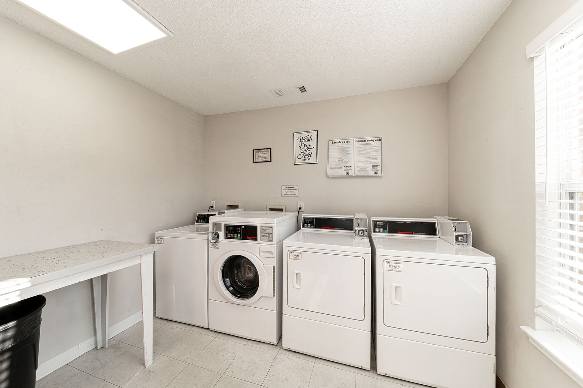 Bright and inviting laundry room featuring modern washing machines and spacious folding area.