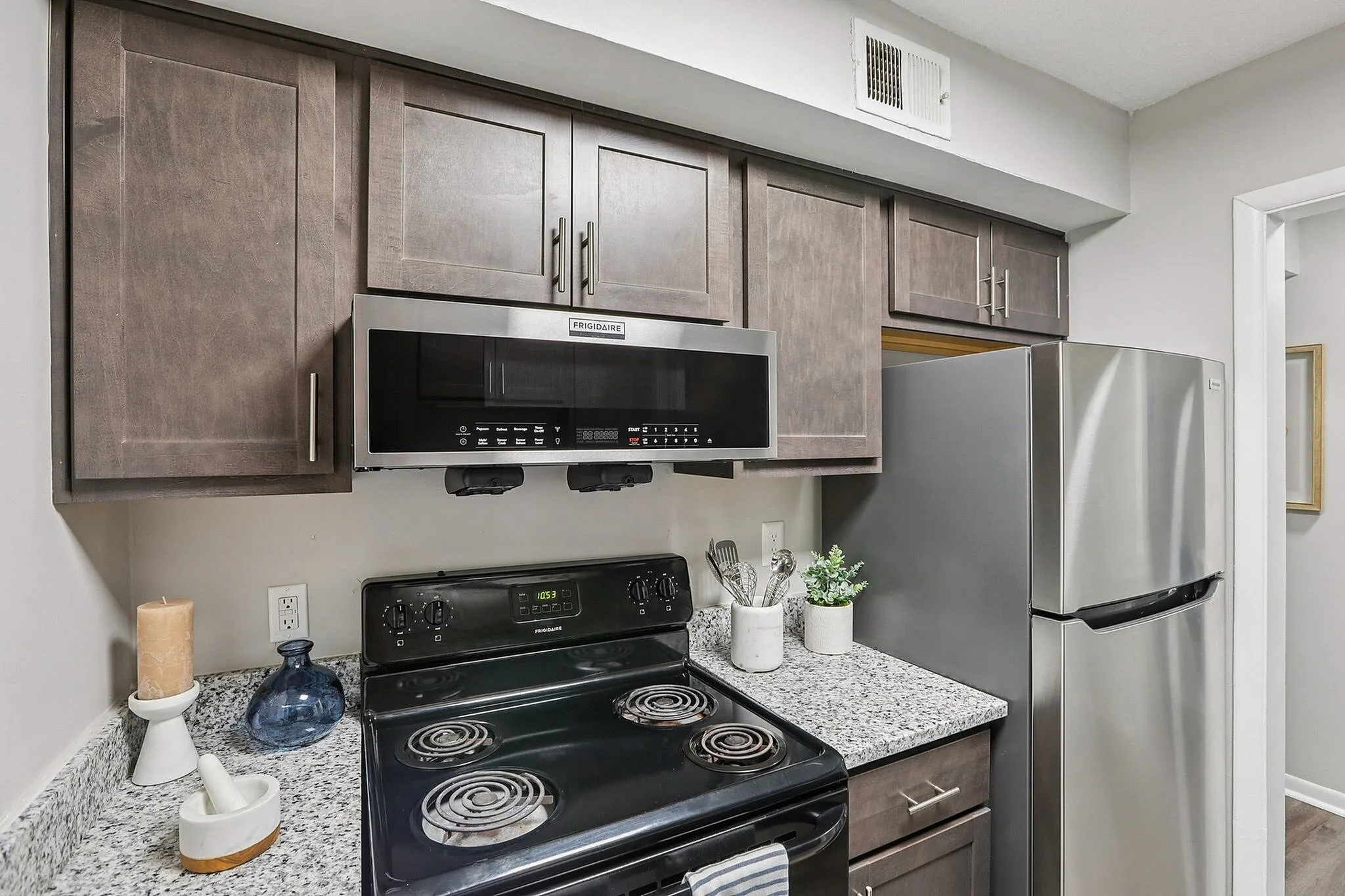 Modern kitchen with sleek dark wood cabinets, stainless steel appliances, and elegant granite countertops.