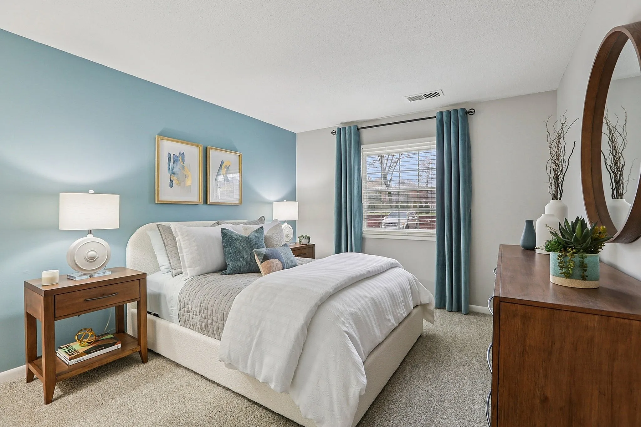Elegant bedroom featuring a plush bed with cozy bedding, stylish wooden furniture, and calming blue accents.