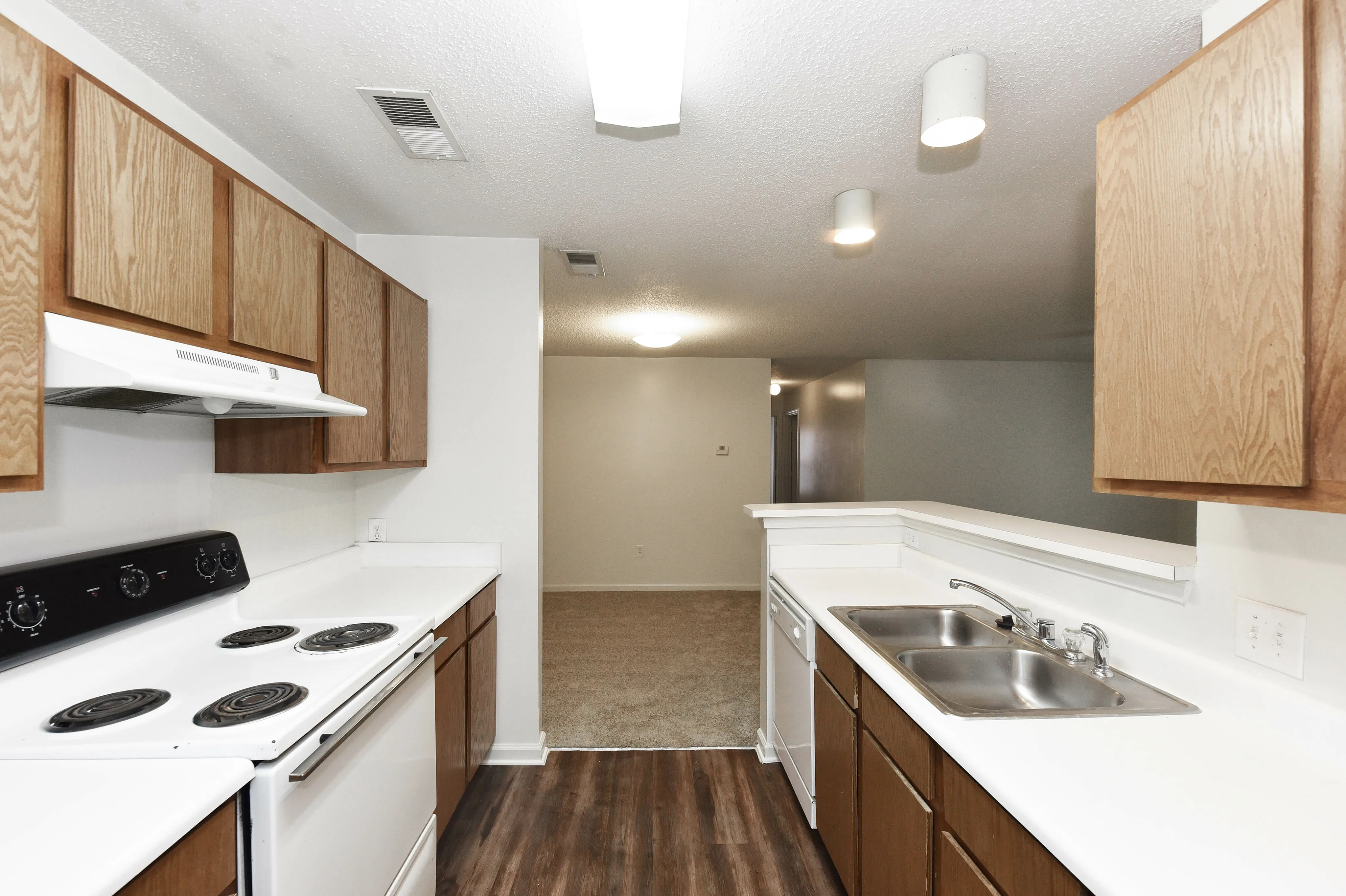 Charming kitchen with wood cabinetry, sleek countertops, and modern appliances leading to an open living area.