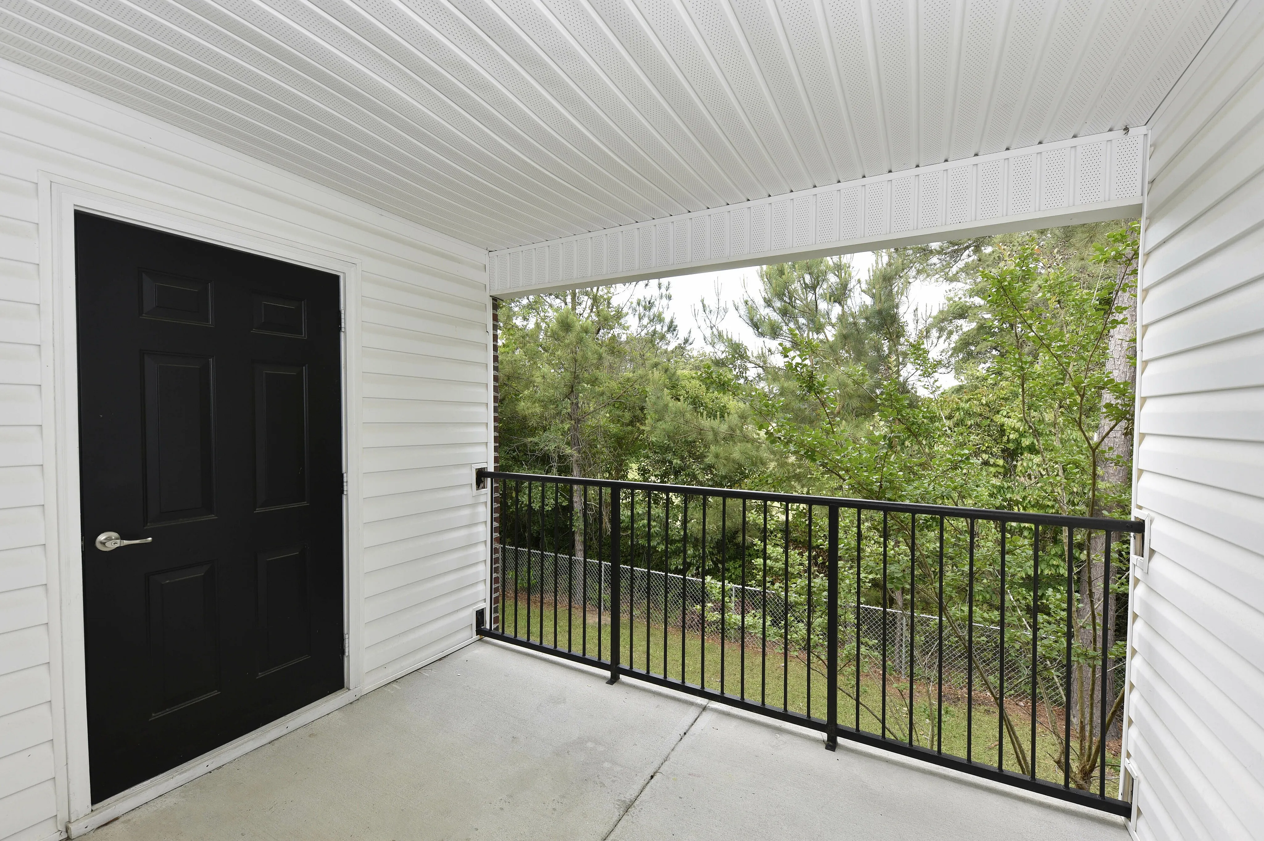Charming balcony with black railing overlooking lush greenery, perfect for relaxation.