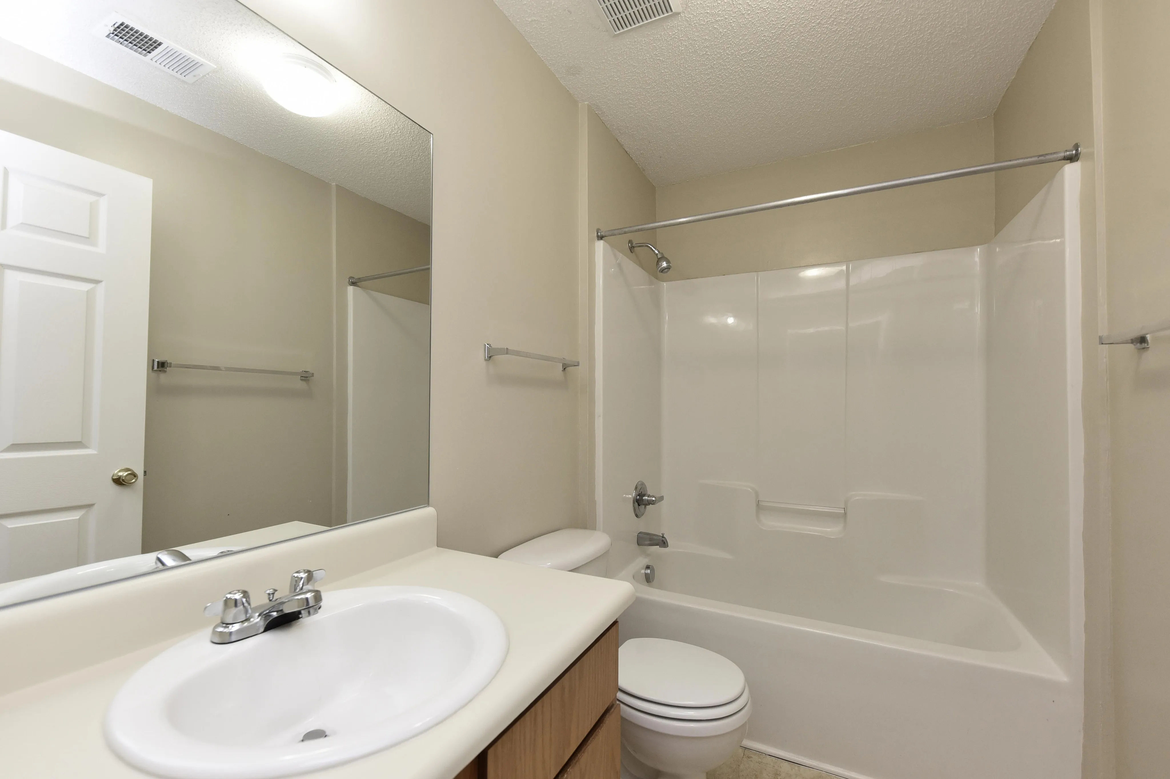 Modern bathroom with elegant beige walls, sleek vanity, and a pristine bathtub-shower combo.
