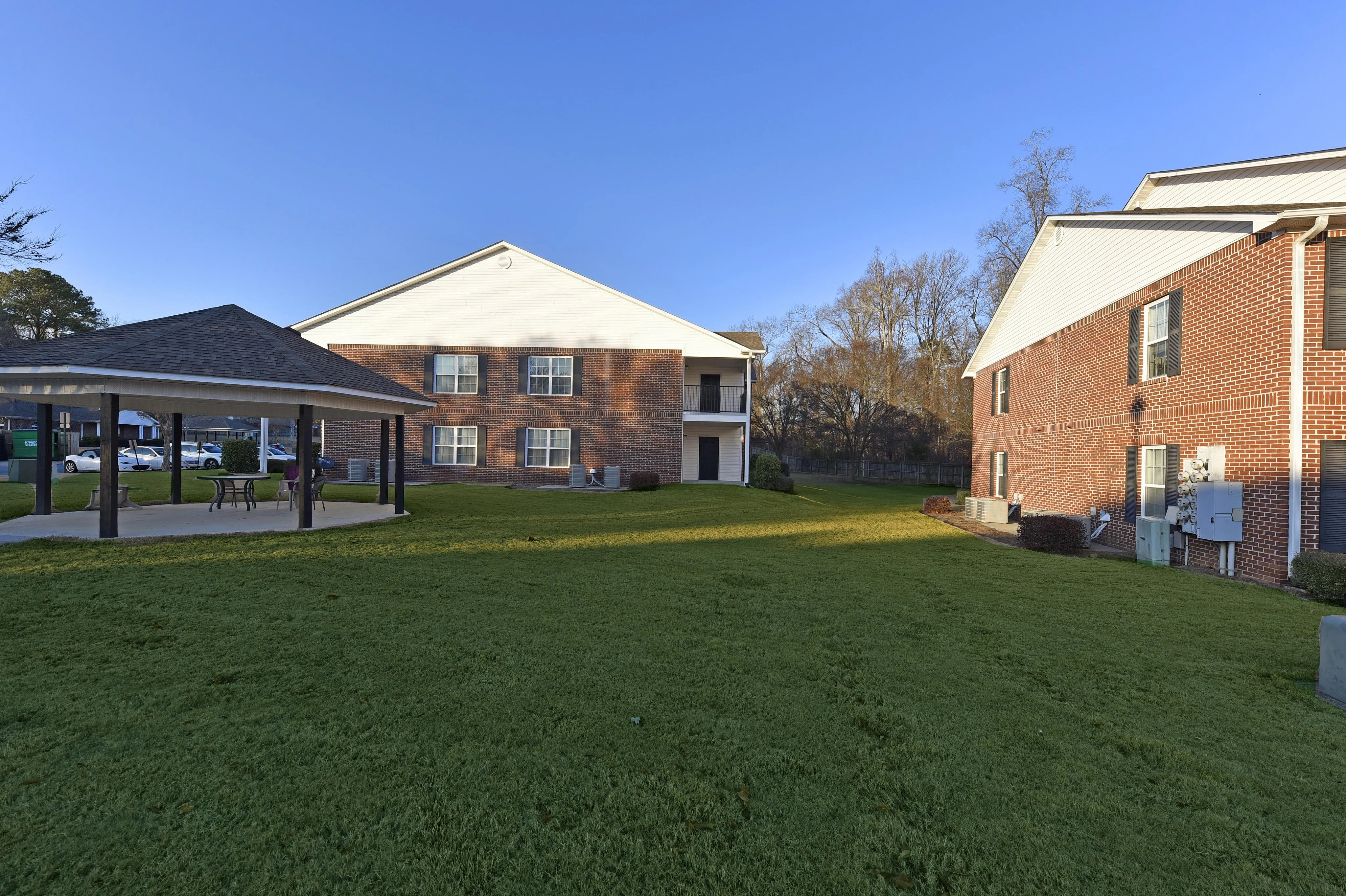 Charming apartment complex with spacious green lawn and inviting gazebo, perfect for relaxation and outdoor gatherings.