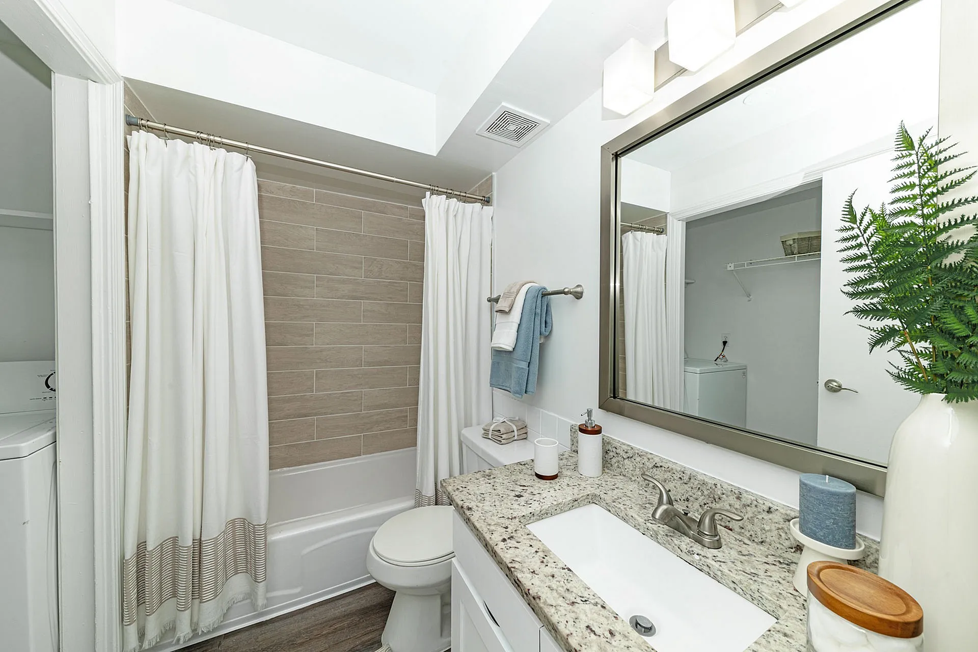 Elegant bathroom with modern granite countertop, stylish mirror, and calming beige tiles, offering a serene retreat.