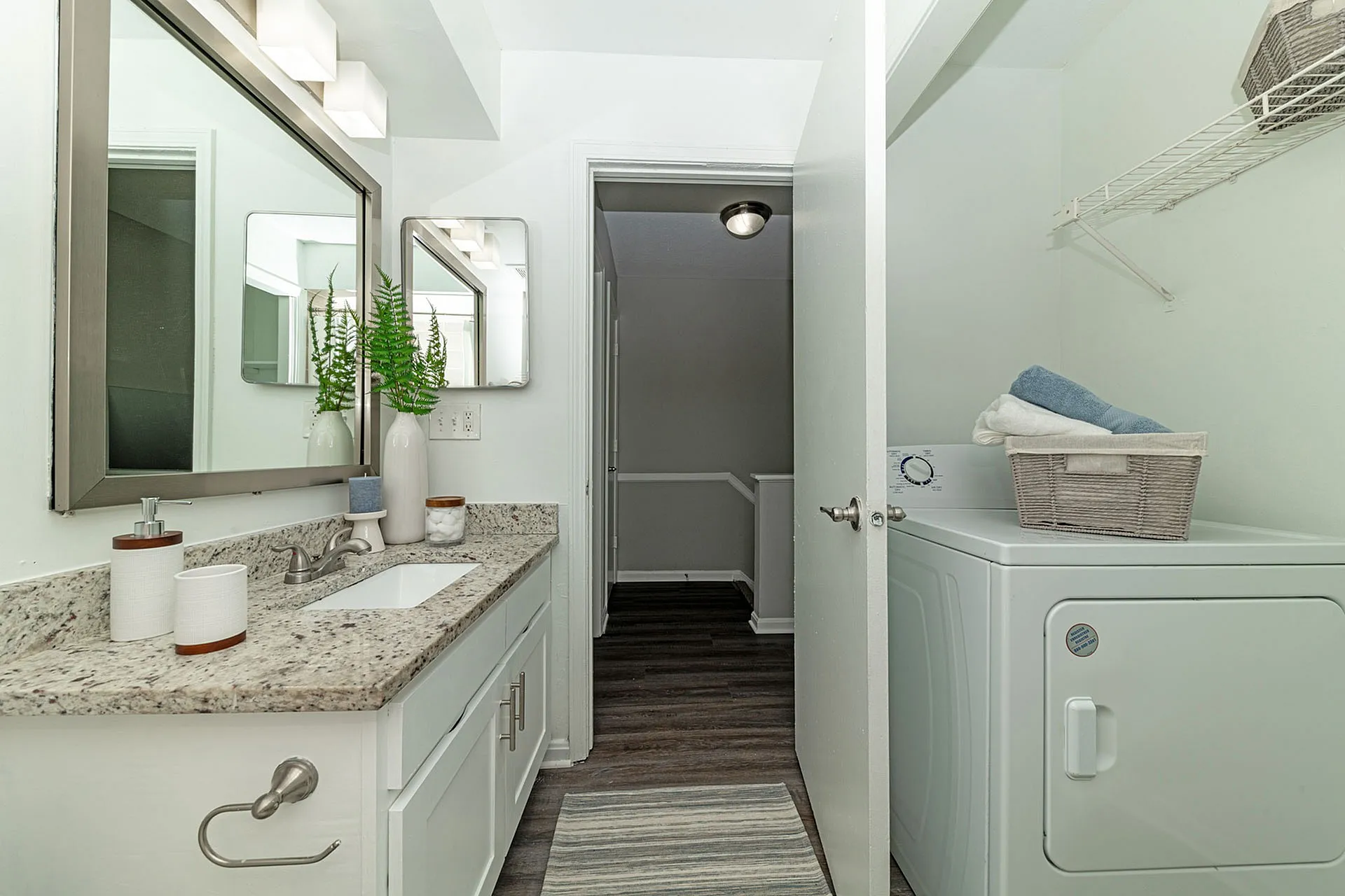 Bright and modern bathroom featuring a sleek granite countertop and a convenient laundry area with a washing machine and neat storage.