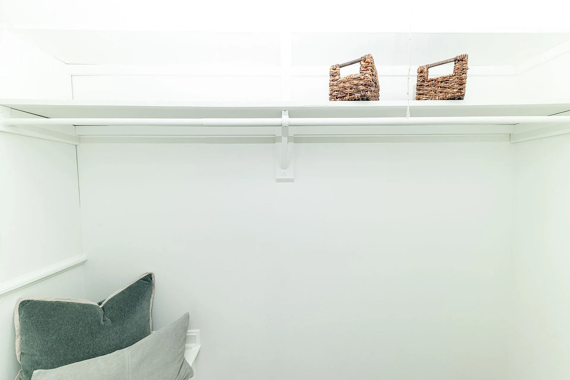 Bright and spacious closet with elegant shelving and stylish wicker baskets, perfect for organized living.