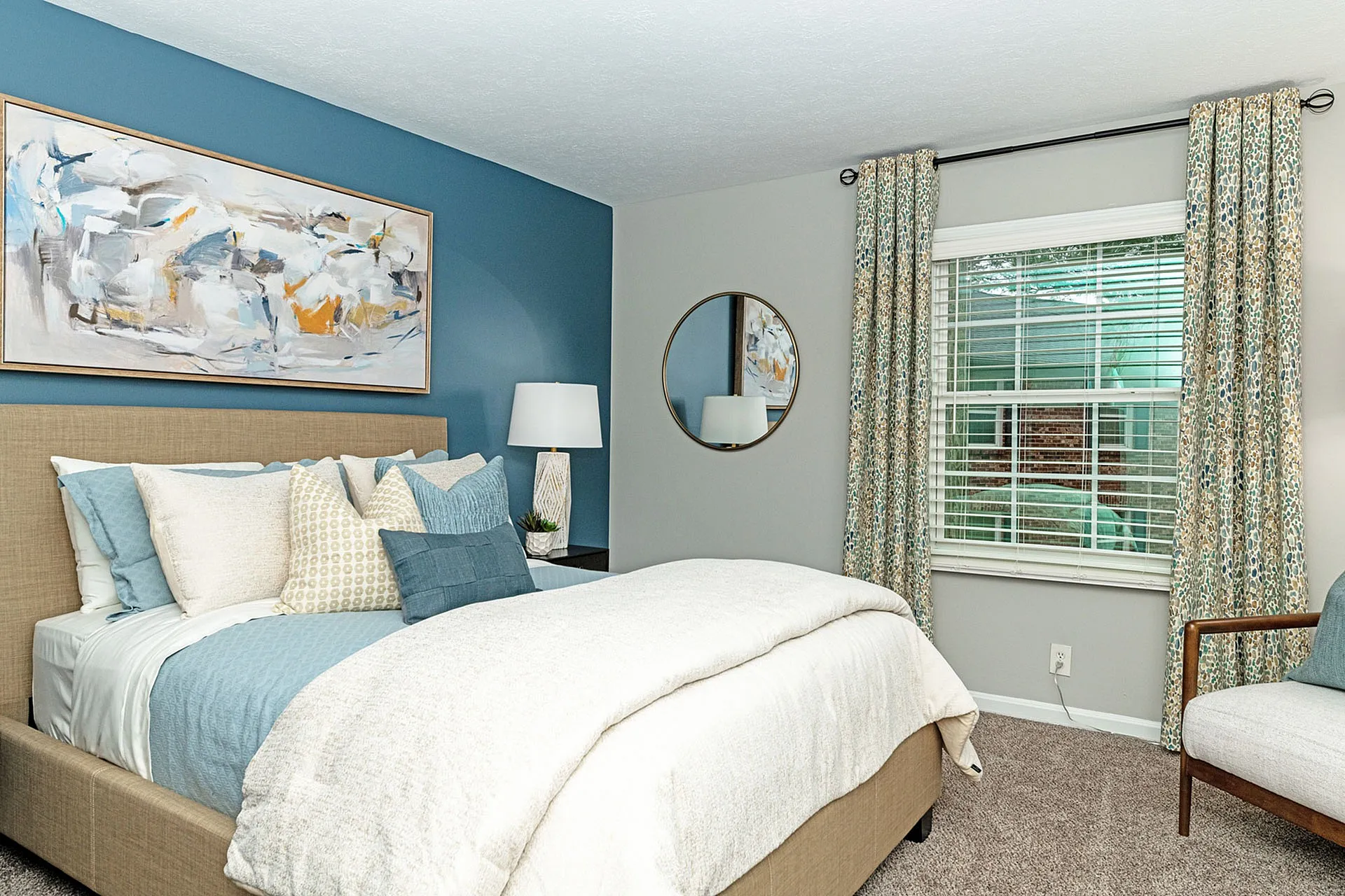 Elegant bedroom with blue accent wall, stylish abstract art, and cozy bedding.