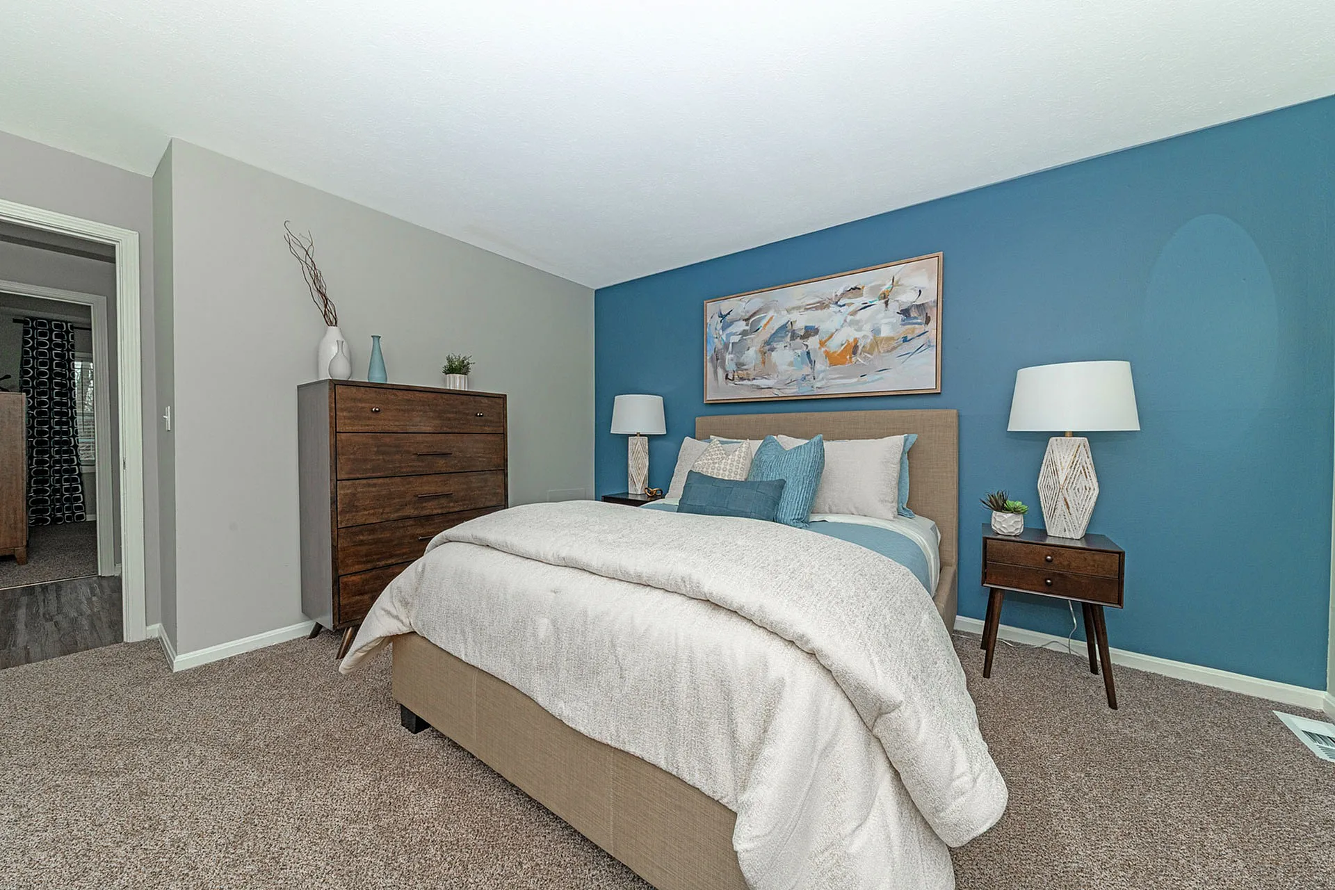 Inviting bedroom with a cozy bed, elegant blue accent wall, and modern decor.