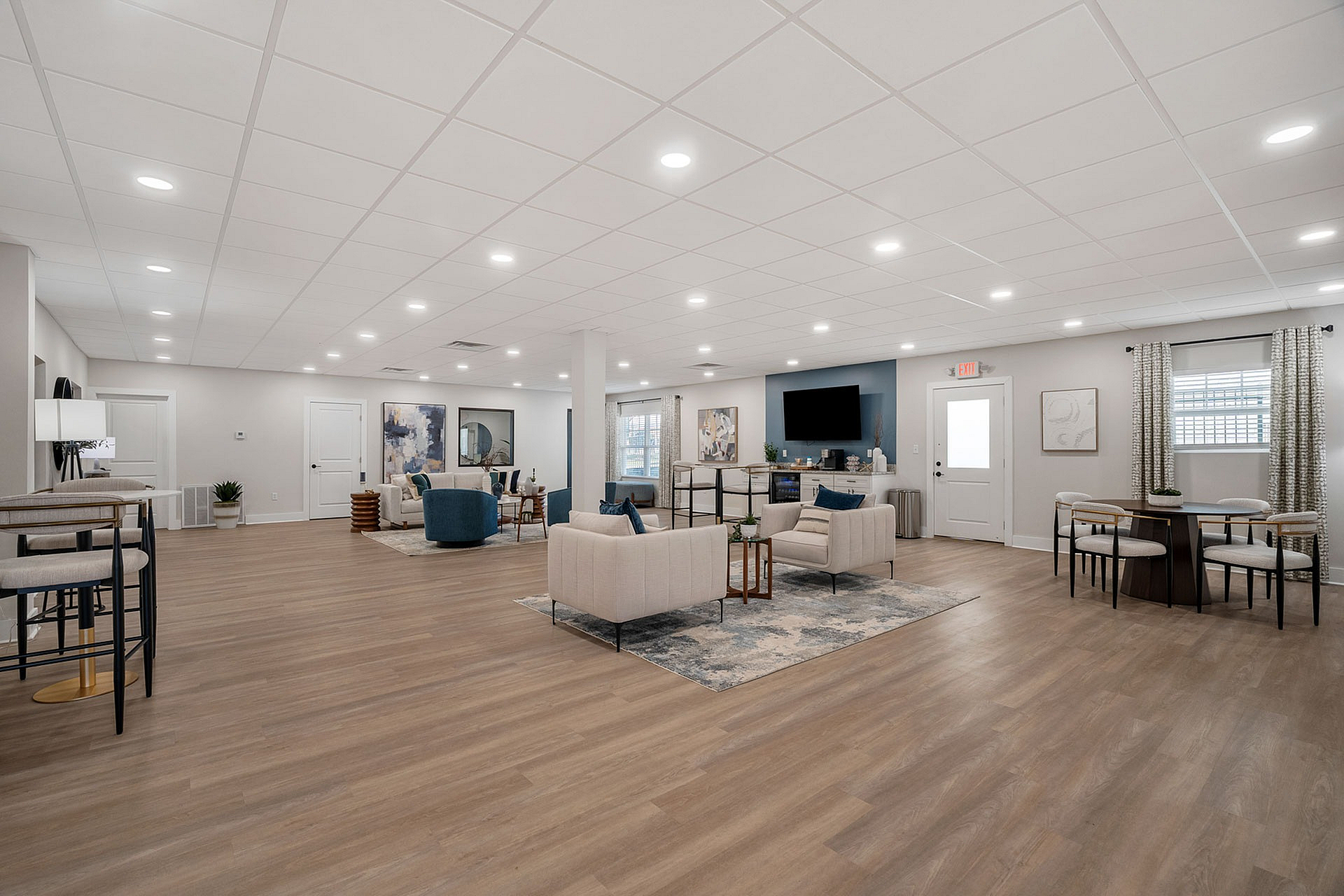 Spacious and modern community lounge with inviting seating, elegant decor, and warm wood flooring, perfect for social gatherings.