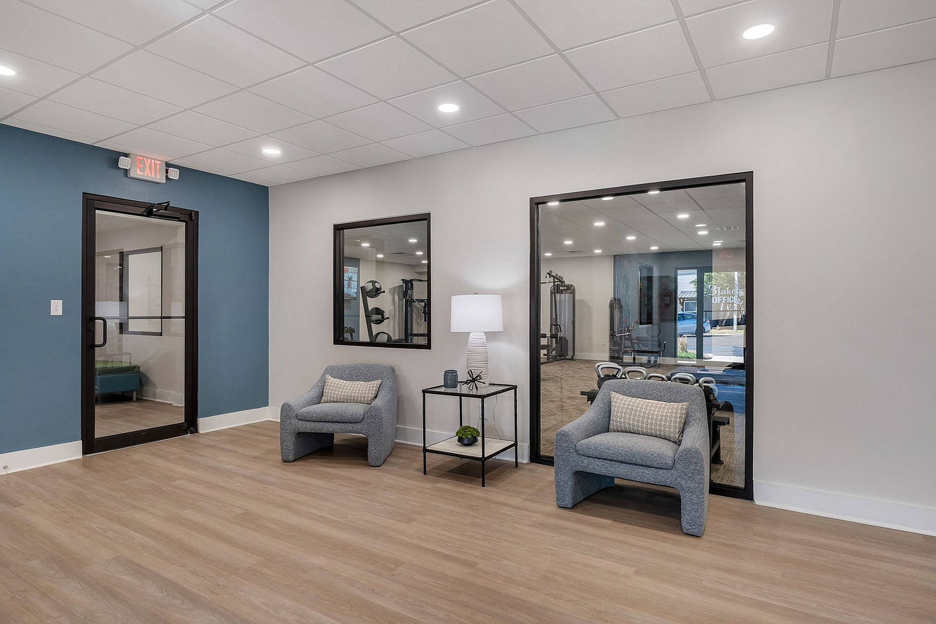 Modern lobby with elegant seating and view of a state-of-the-art gym, showcasing style and convenience.