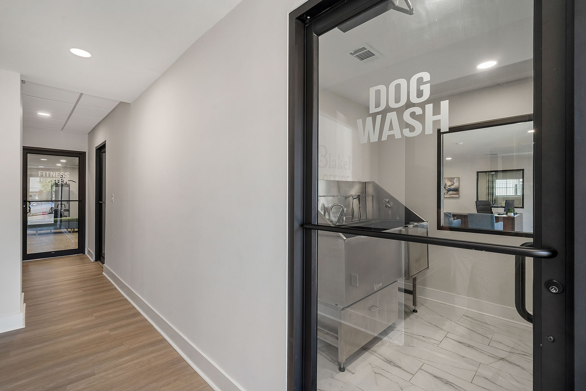 Modern apartment amenity hallway featuring a sleek dog wash station and a state-of-the-art fitness center.