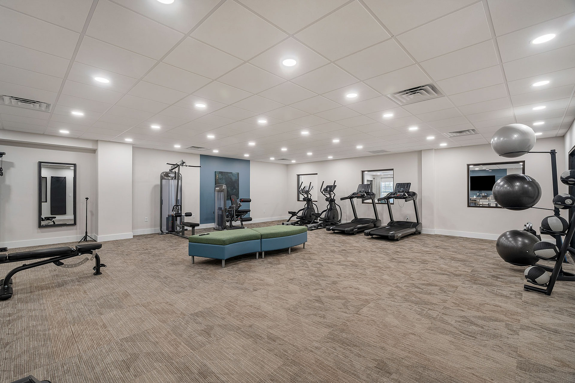 Luxurious, well-lit fitness center featuring modern equipment including treadmills, strength machines, and yoga balls, ideal for an energizing workout.