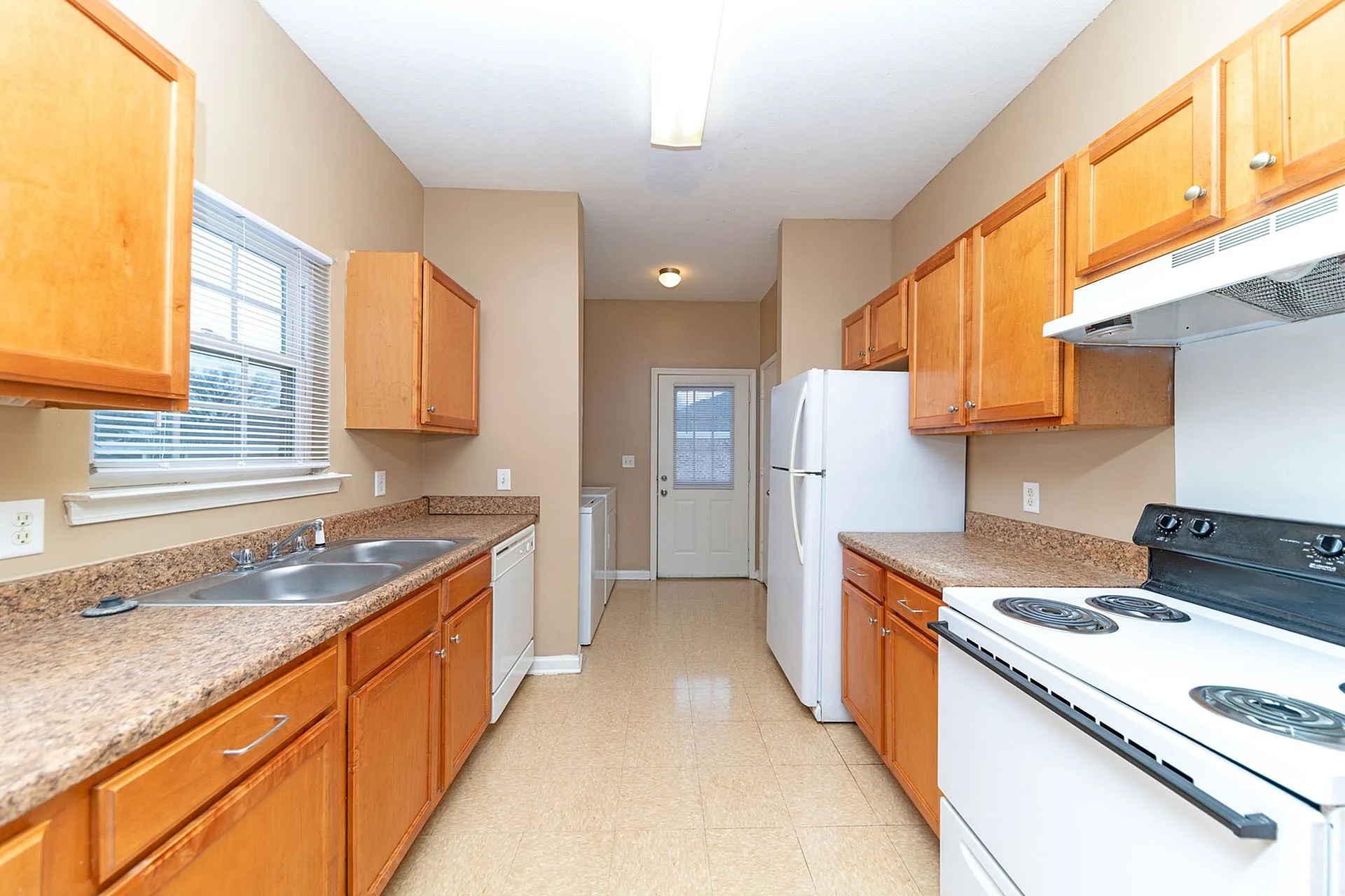 Charming galley-style kitchen featuring warm wooden cabinetry, modern appliances, and ample counter space for culinary creativity.