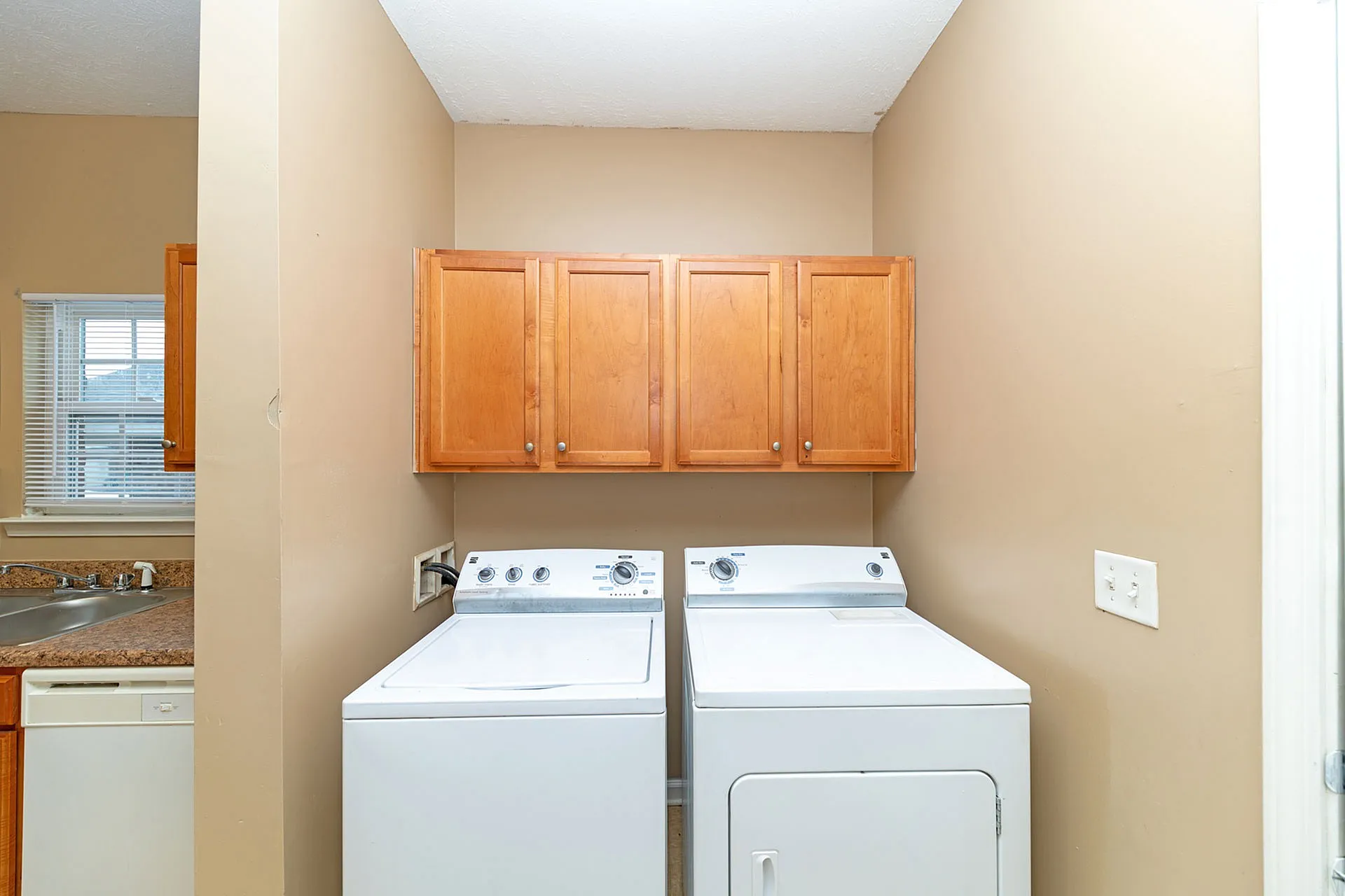 Bright utility area featuring modern washer and dryer with elegant wooden cabinetry for added storage.