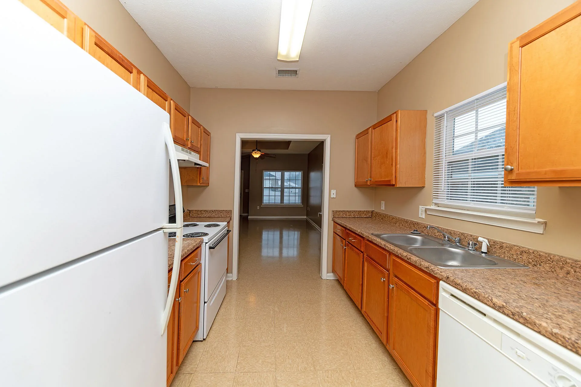 Bright and inviting kitchen featuring sleek countertops, modern appliances, and ample cabinetry with a view into the cozy living area.