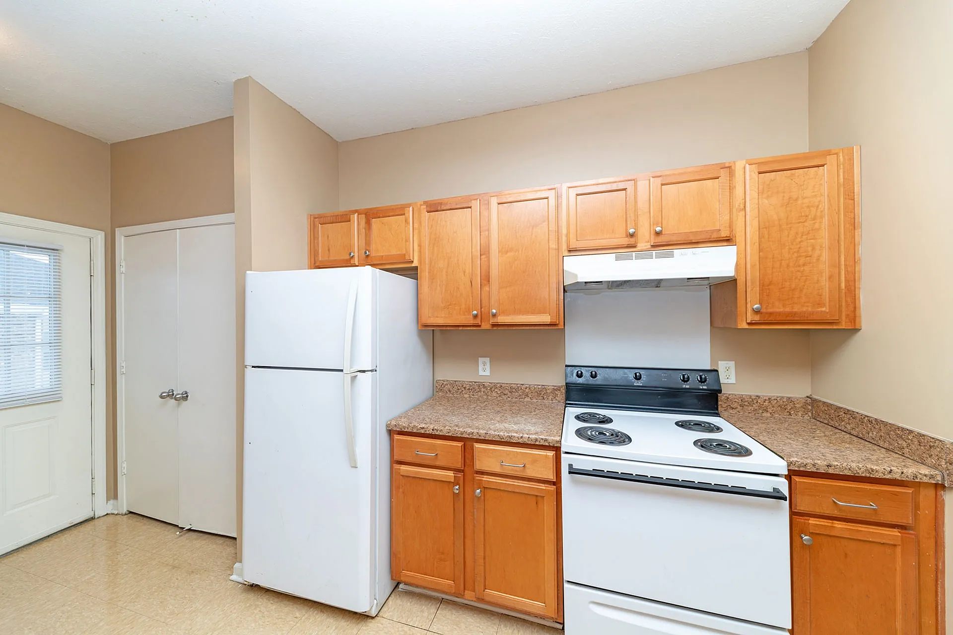 Bright kitchen with warm wooden cabinets, sleek white appliances, and spacious countertops.