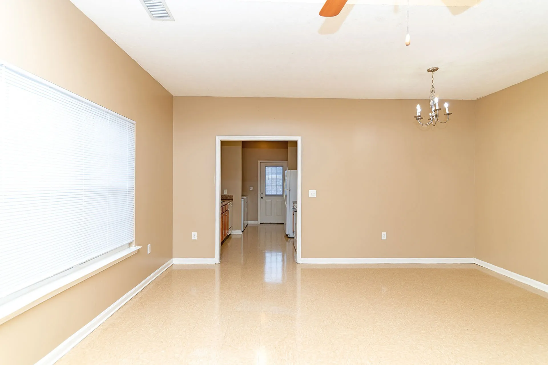 Bright and inviting living area with warm tones, modern chandelier, and ample natural light perfect for gatherings.