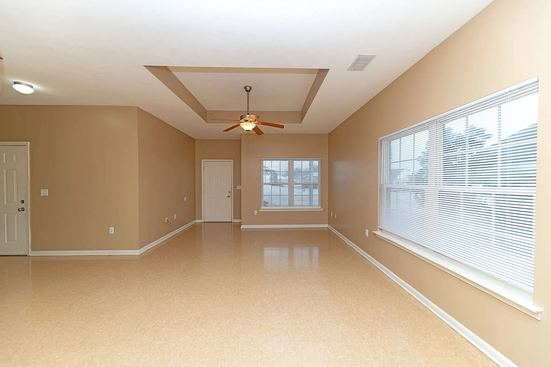 Bright, spacious living room with modern ceiling fan and large windows, offering abundant natural light.