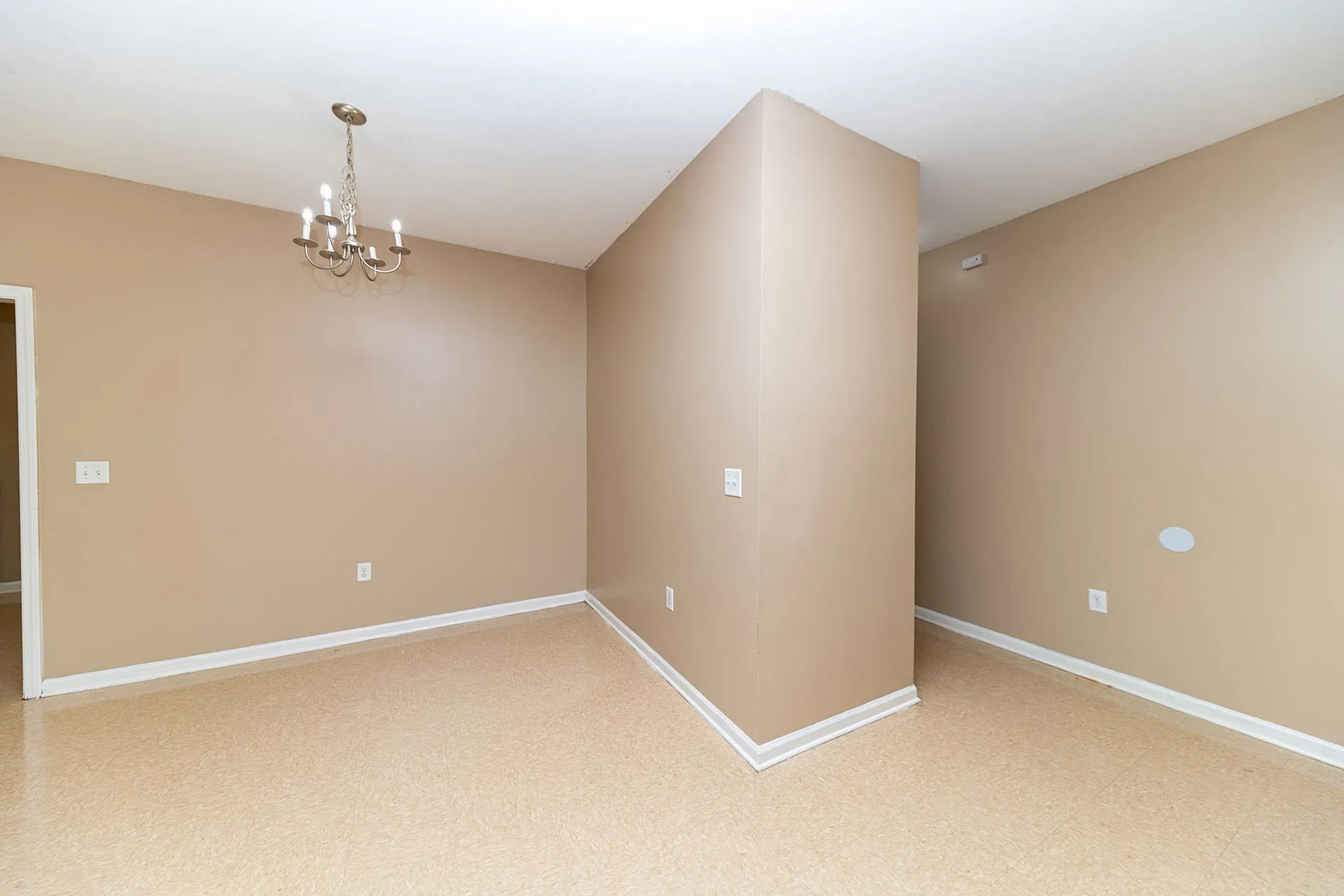 Elegant room showcasing warm beige walls, stylish light fixture, and polished flooring, perfect for versatile living space.