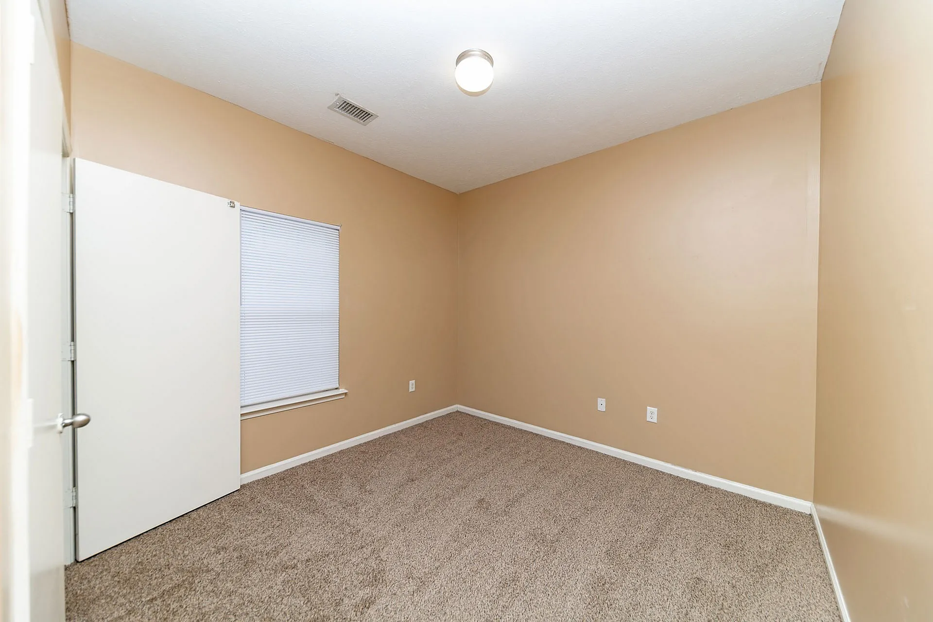 Inviting room with plush carpet and warm beige walls, perfect for a cozy and comfortable atmosphere.