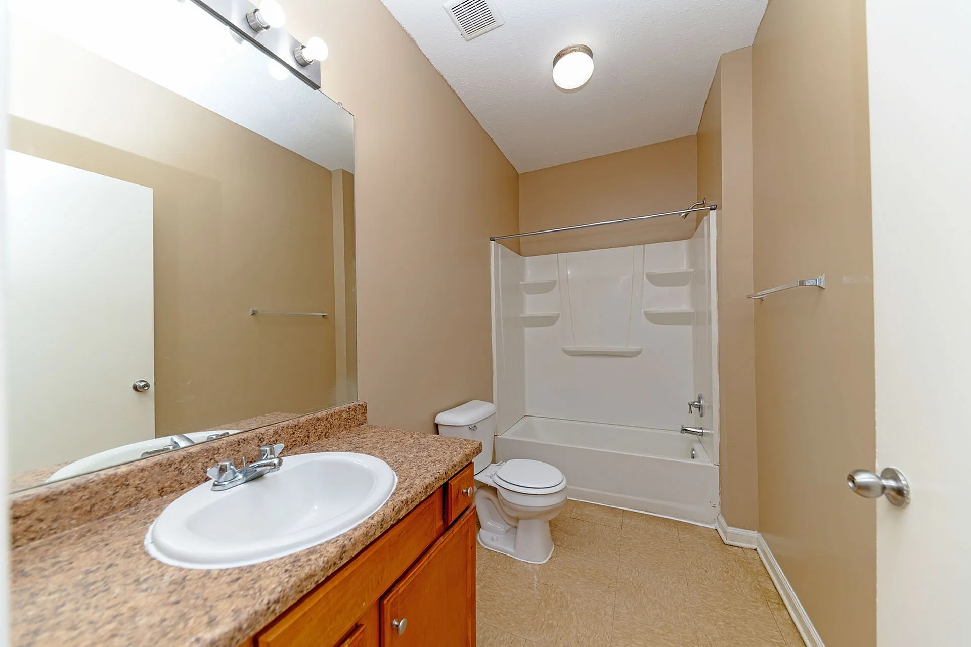 Inviting bathroom with sleek fixtures, a granite countertop sink, and a full bathtub, offering a clean and modern design.