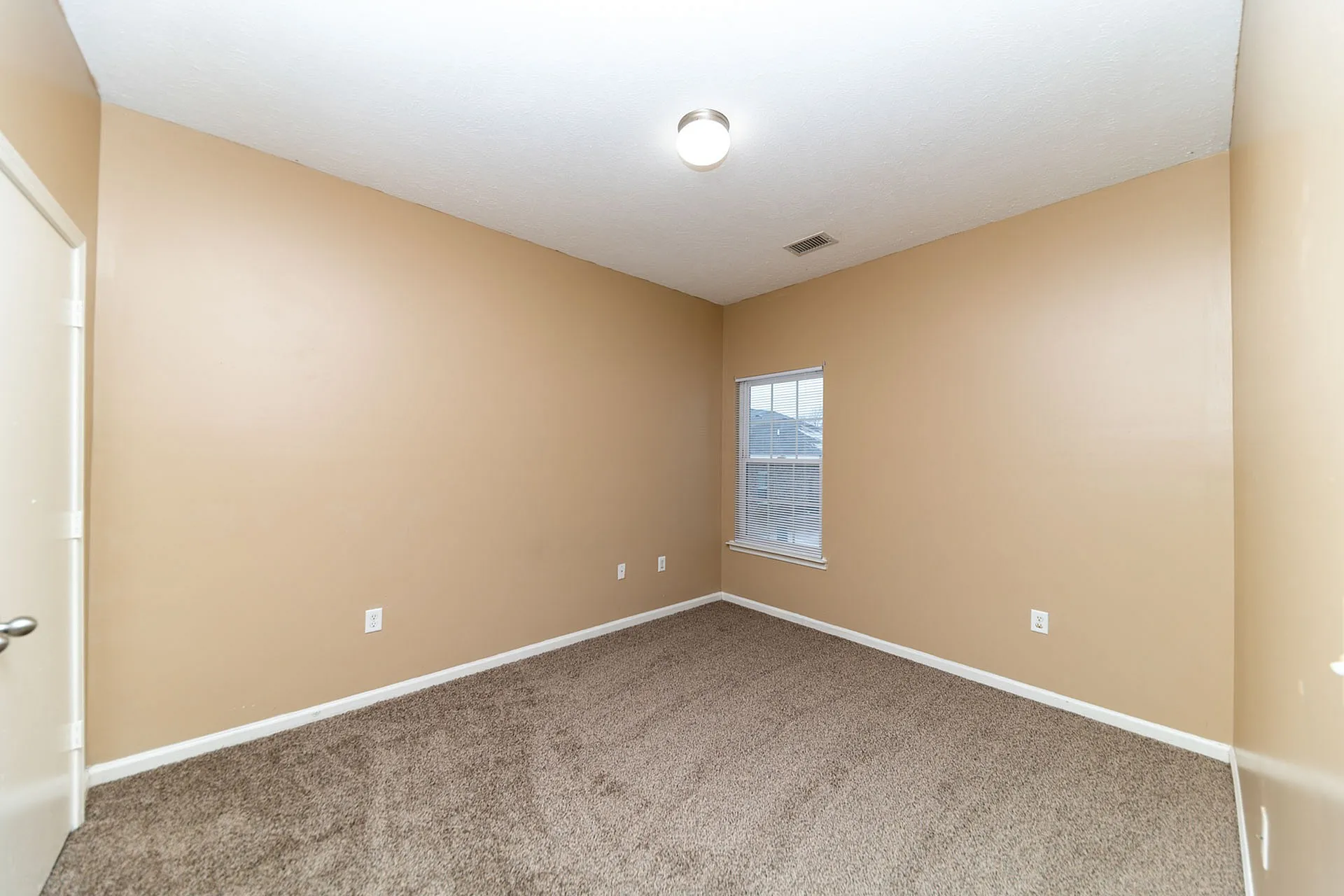 Bright, spacious room with soft beige walls and plush carpet, perfect for a cozy bedroom or home office.