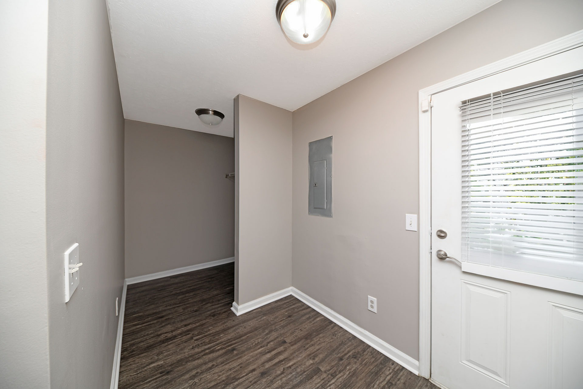 Chic entryway with modern lighting and sleek wood flooring, leading to a welcoming space with natural light.