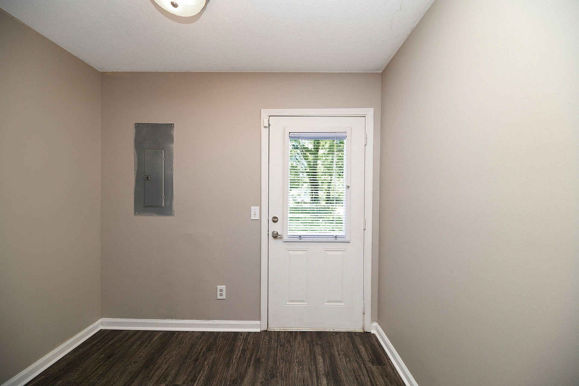Charming entryway with modern flooring and abundant natural light through a windowed door.