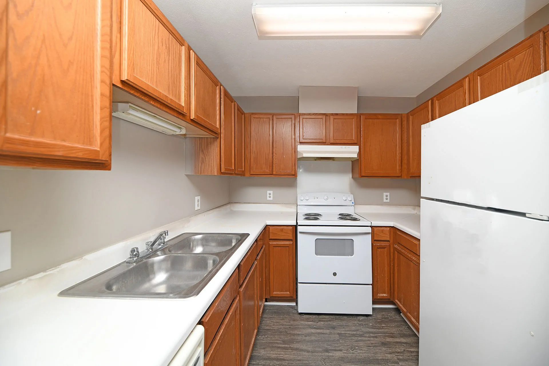 Inviting kitchen featuring ample wooden cabinets, sleek countertops, modern appliances, and a double sink, perfect for culinary enthusiasts.