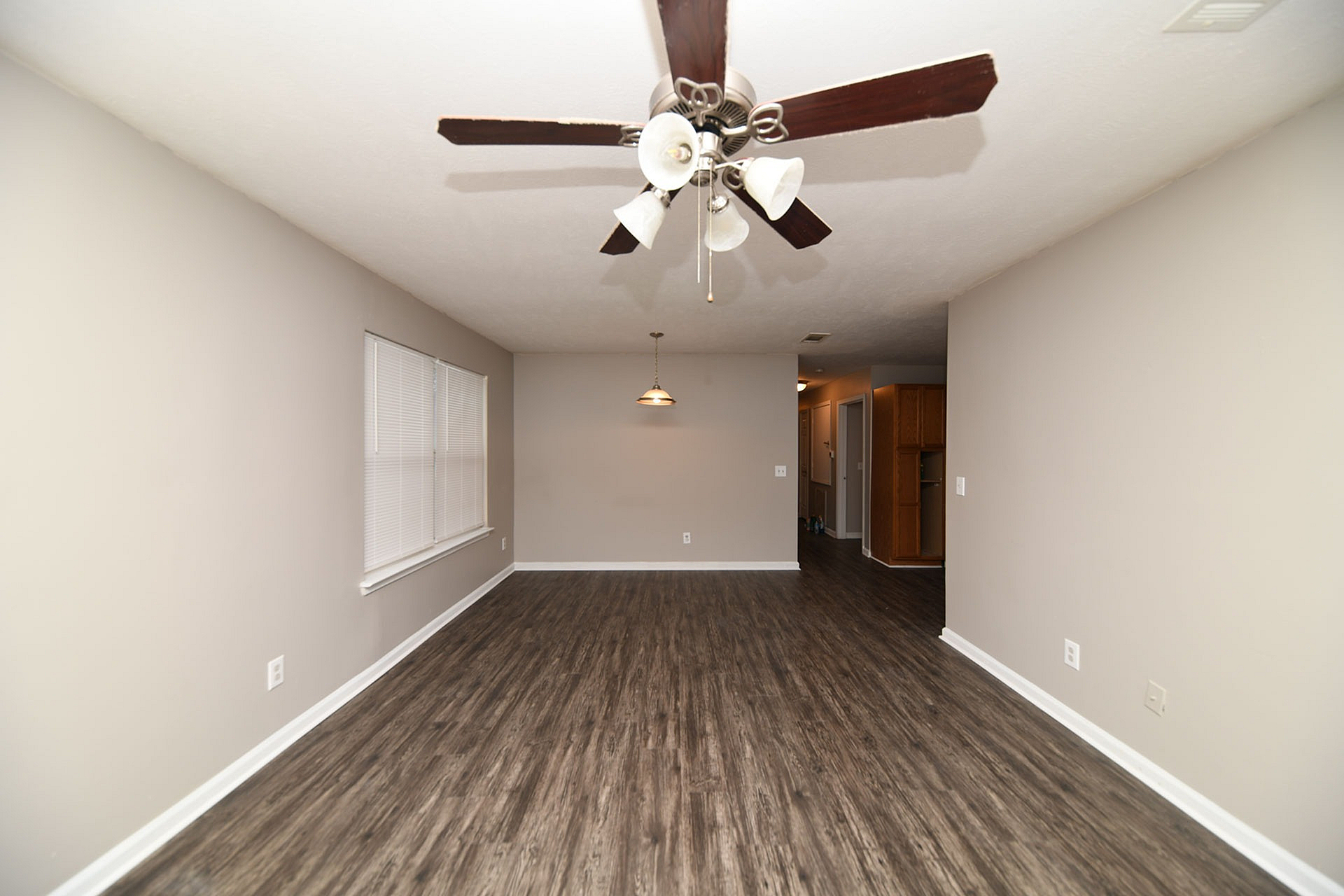 Spacious living area with elegant hardwood floors and modern ceiling fan, perfect for cozy living and entertaining.