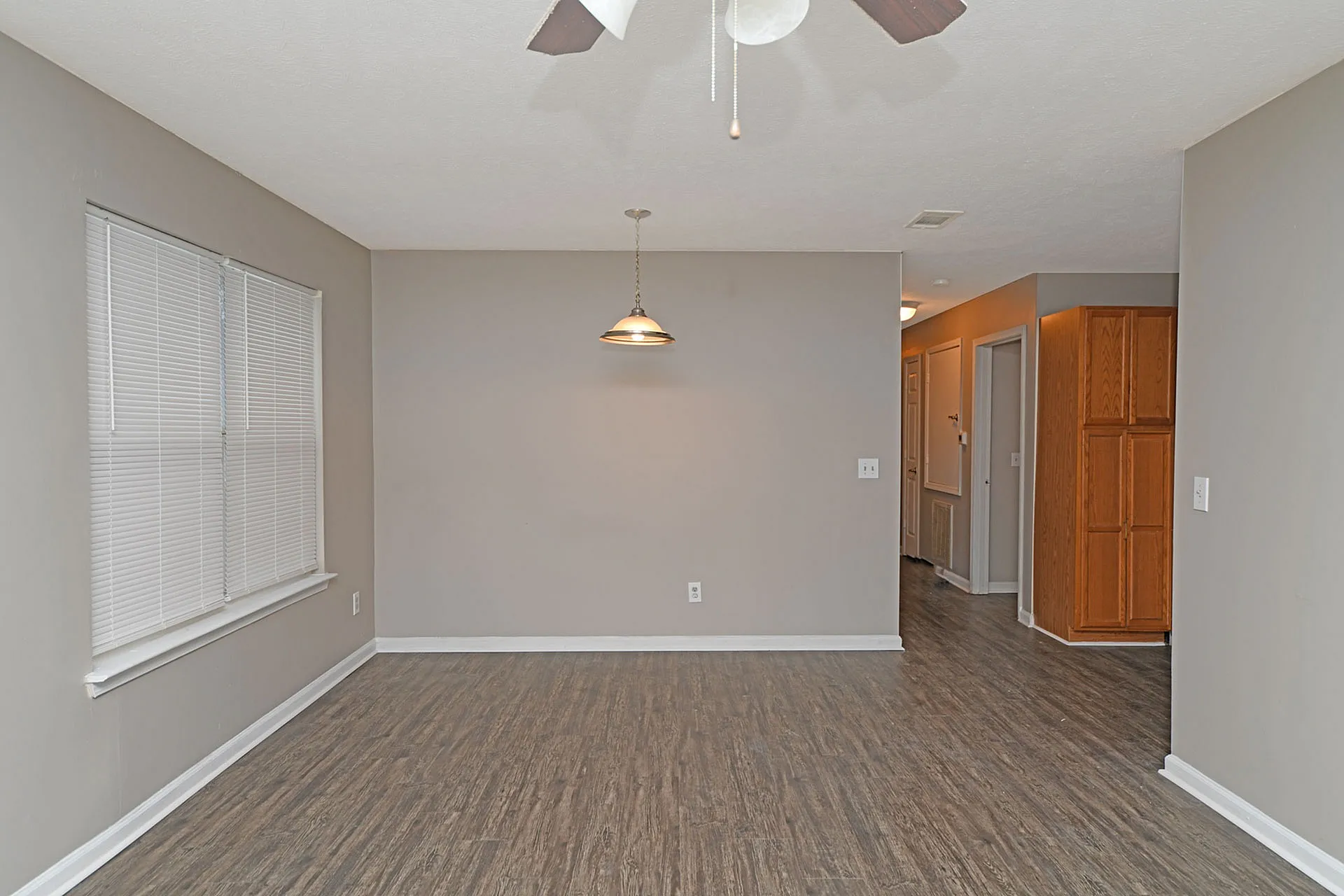 Modern apartment interior showcasing elegant wood flooring, neutral walls, and stylish lighting, leading into a cozy hallway.