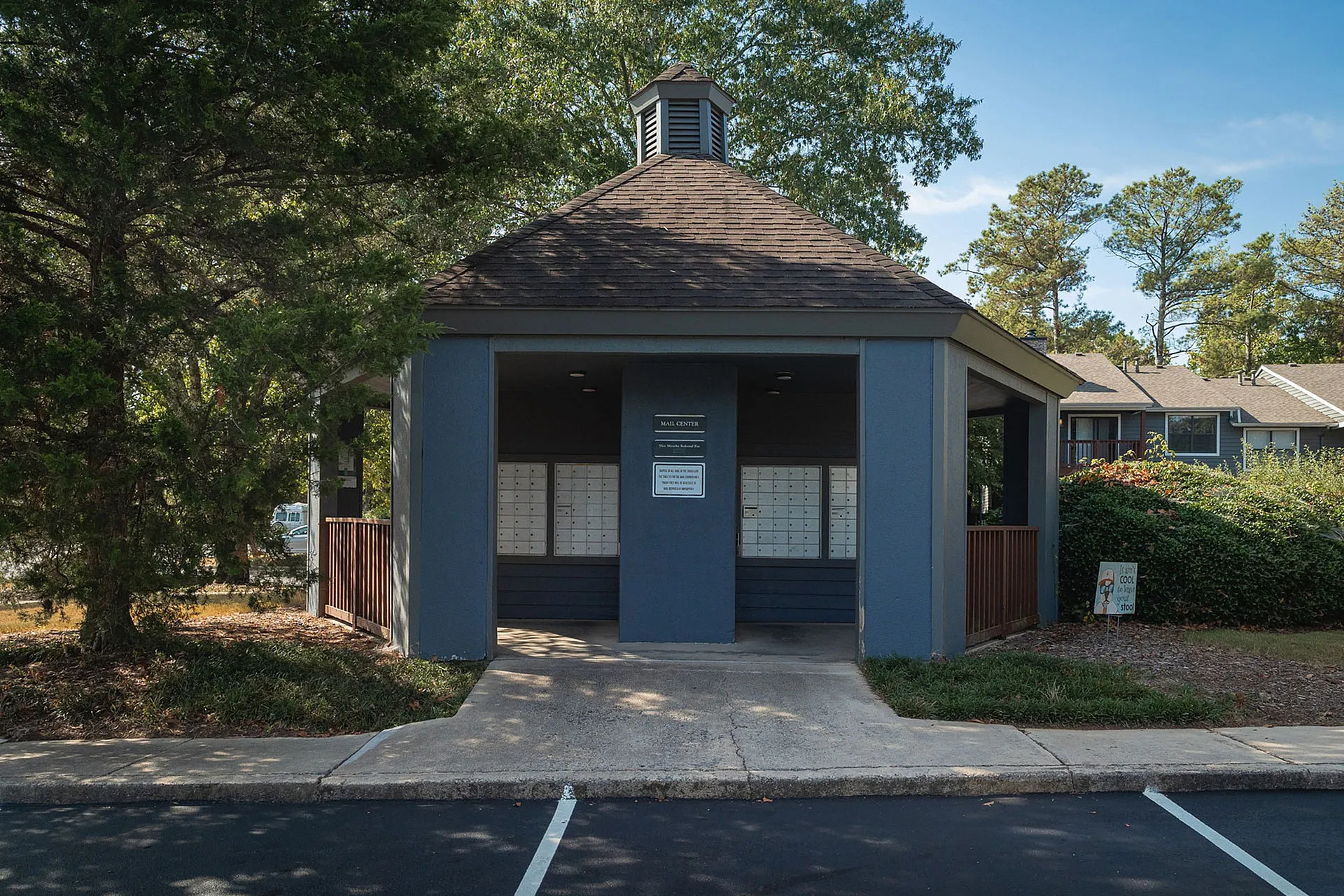 Cozy community mail center with a shaded roof and welcoming pathway, surrounded by greenery.