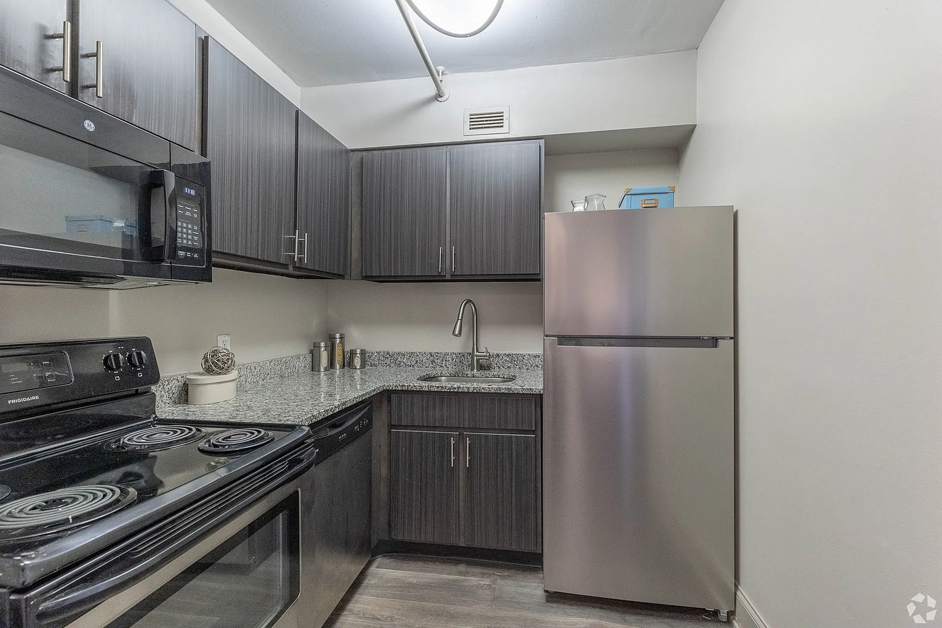 Modern kitchen with sleek dark cabinetry, stainless steel appliances, and elegant granite countertops.