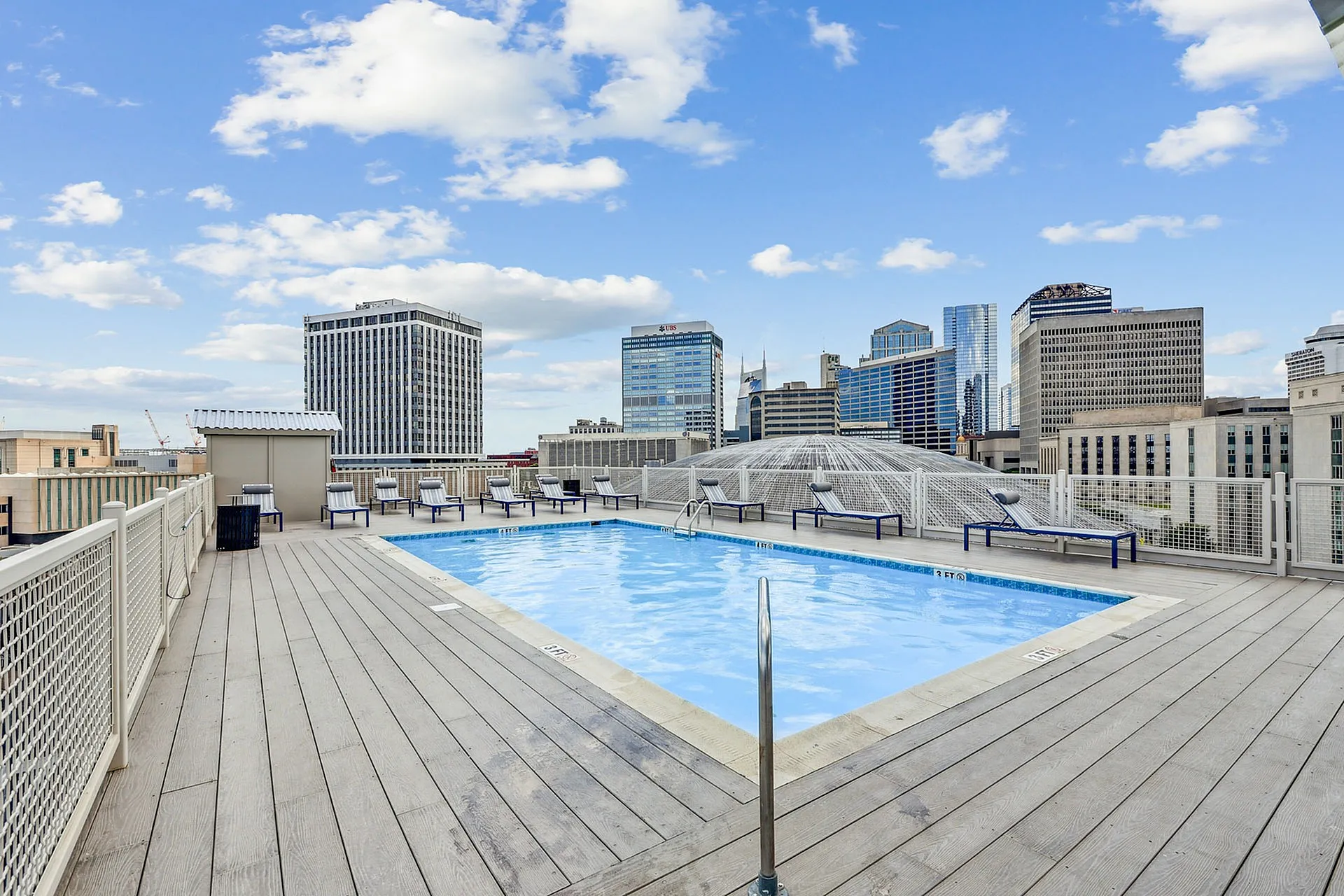 Rooftop oasis featuring a sparkling swimming pool with stunning cityscape views and surrounding lounge chairs for relaxation.