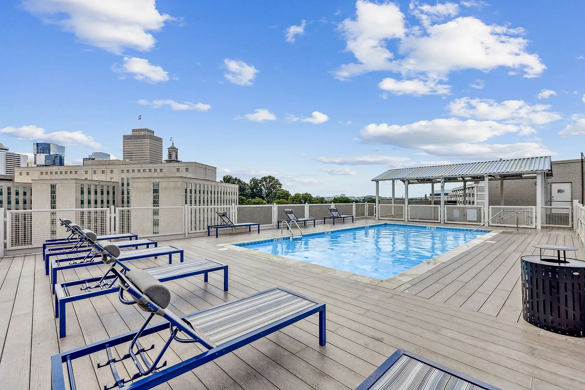 Luxurious rooftop pool area with lounge chairs and stunning city skyline views, perfect for relaxation and leisure.