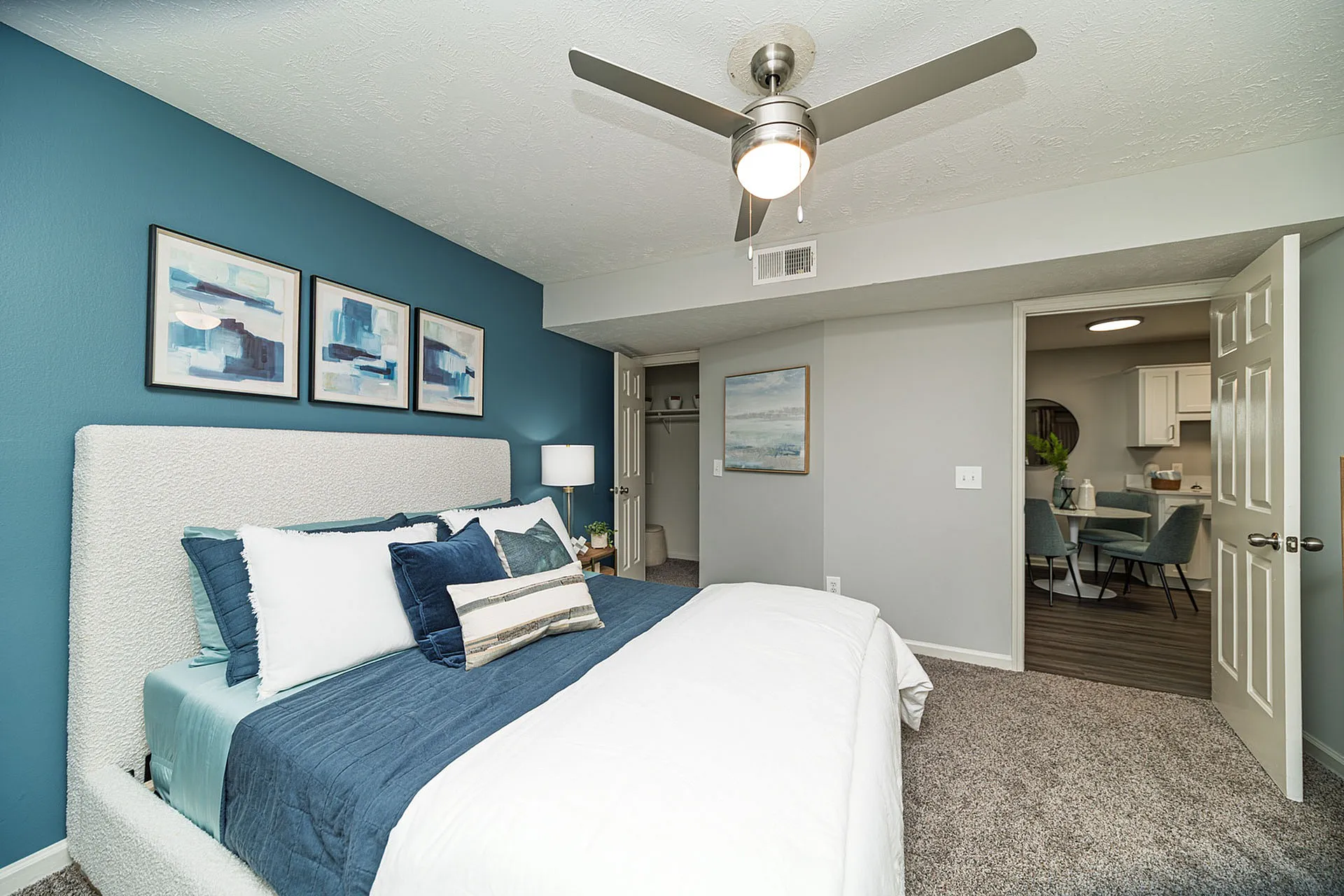 Inviting bedroom with modern decor, featuring a plush bed, stylish artwork, and seamless flow into a cozy dining area.