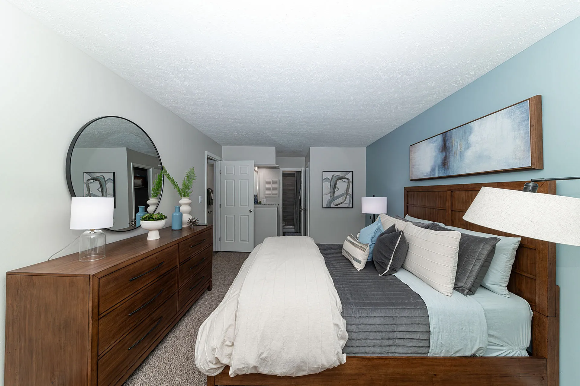 Inviting bedroom with soft blue accents, large wooden dresser, and contemporary decor for a serene retreat.