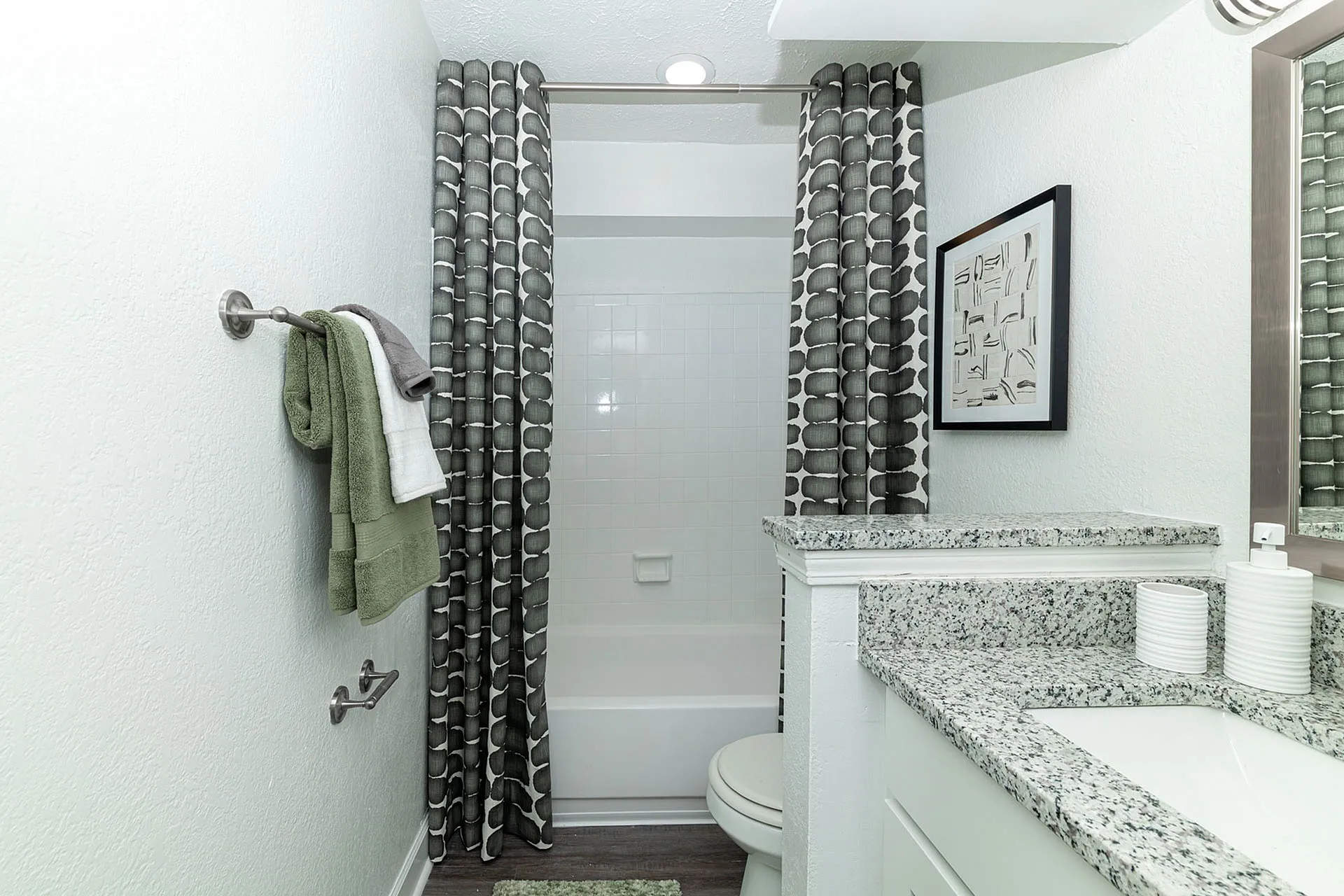 Modern bathroom with elegant granite countertop, stylish patterned shower curtain, and contemporary wall art for a serene atmosphere.