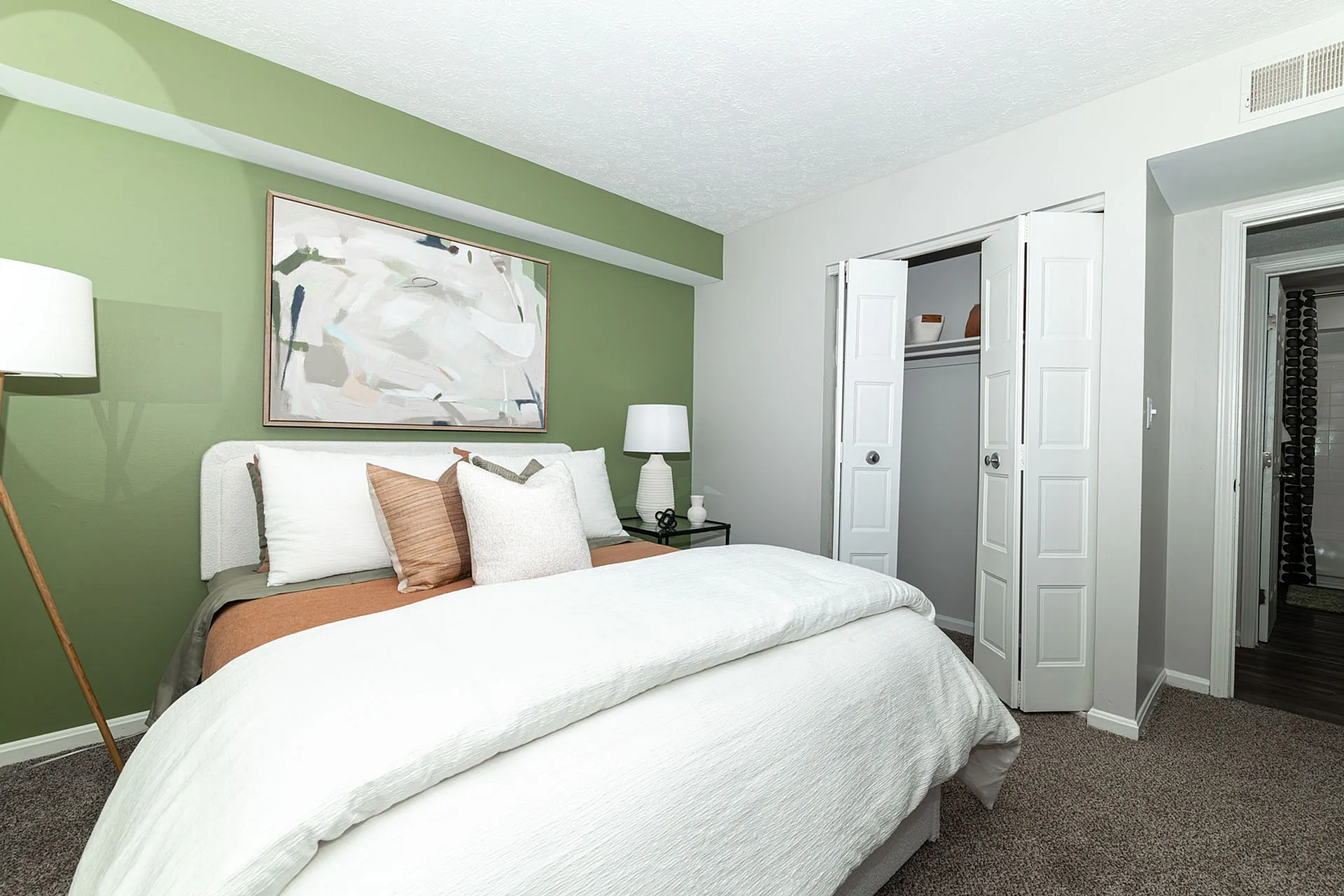 Cozy bedroom with elegant decor featuring a soft green accent wall, modern art, and plush bedding for ultimate comfort.