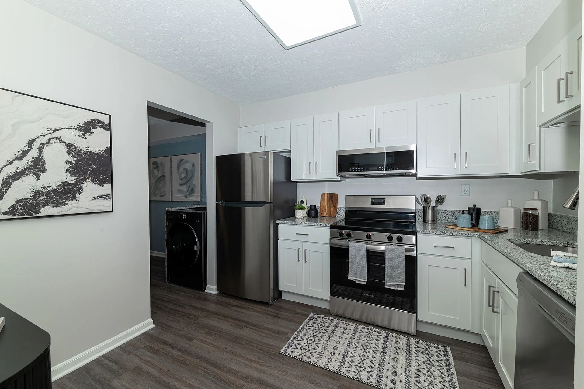 Modern kitchen with sleek stainless steel appliances, white cabinetry, and stylish dark wood flooring creating a sophisticated culinary space.