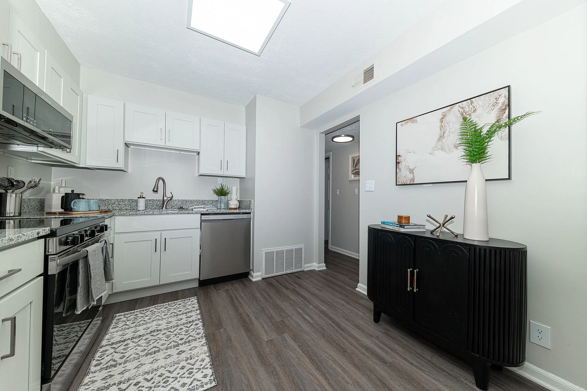 Modern kitchen layout featuring sleek white cabinetry, stainless steel appliances, and elegant granite countertops, complemented by stylish decor and natural lighting.