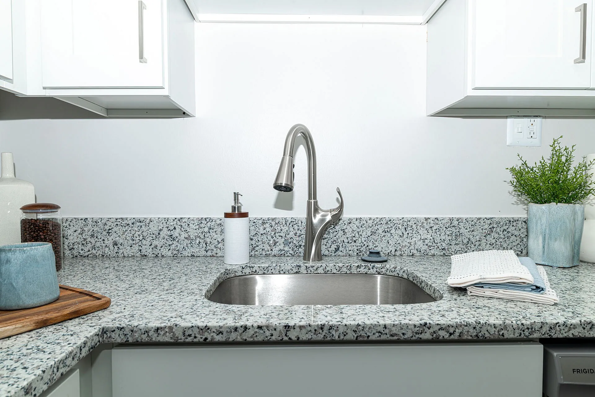 Modern kitchen featuring elegant granite countertops, chic white cabinets, and a stylish stainless steel faucet with ample natural light.